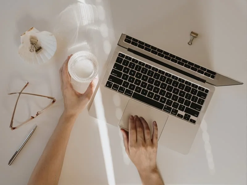 Innerbloom Studio overhead flat lay of a web design workspace with a laptop, coffee cup, and glasses