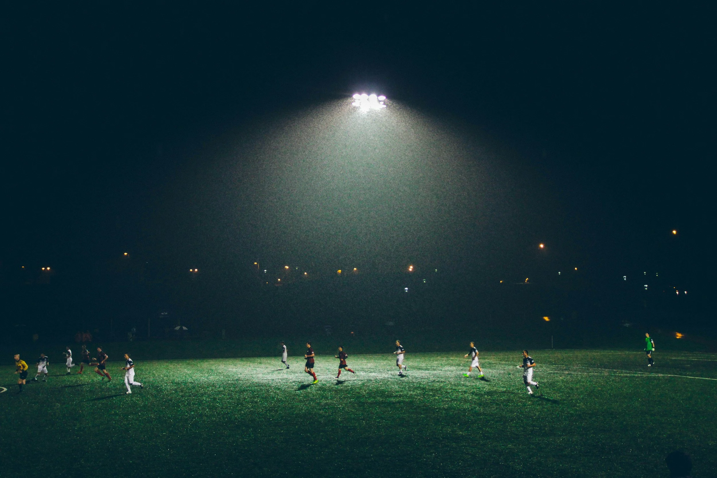 Nighttime soccer match with players on field under floodlights.