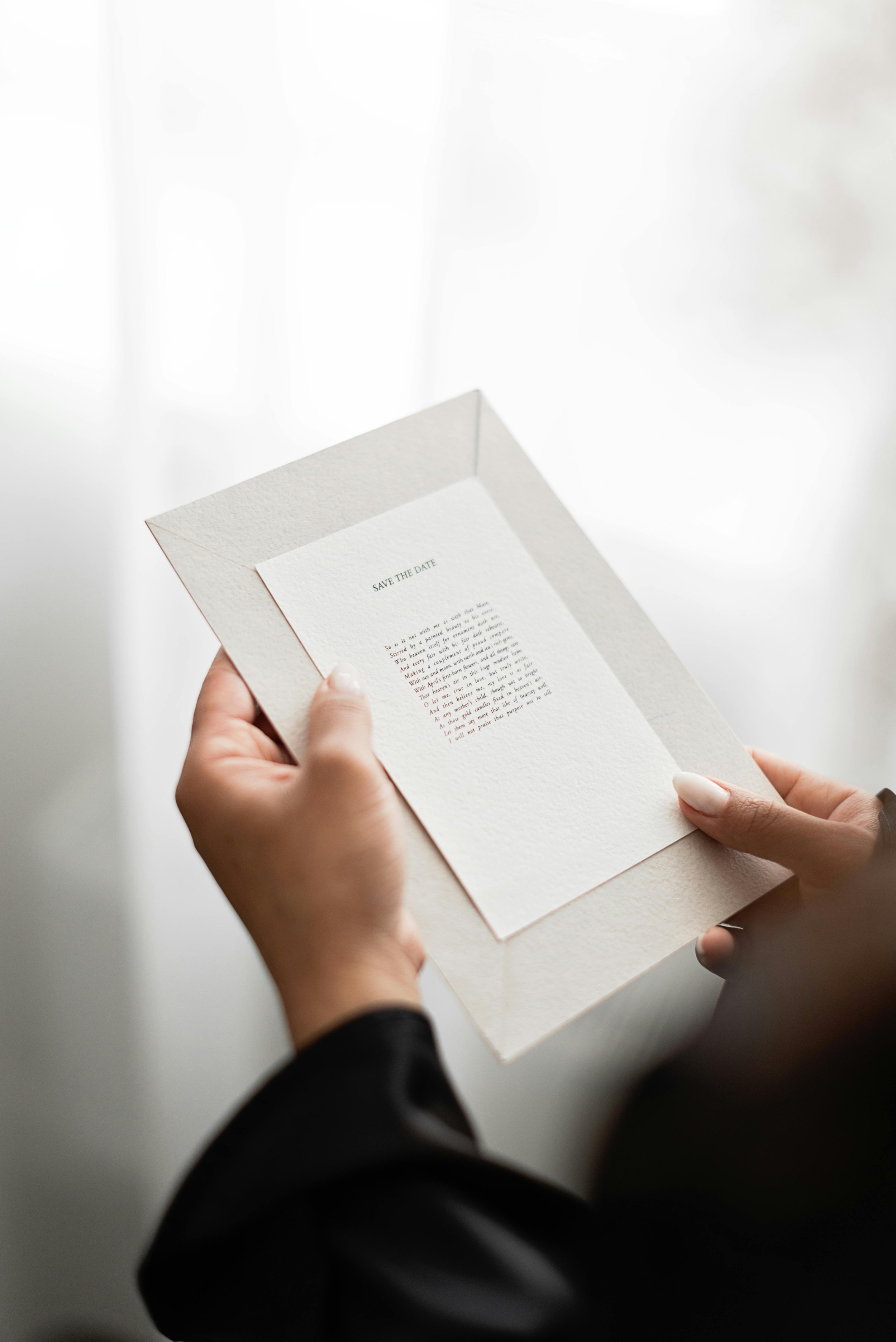 Person holding an open white card with printed text on a plain white background.