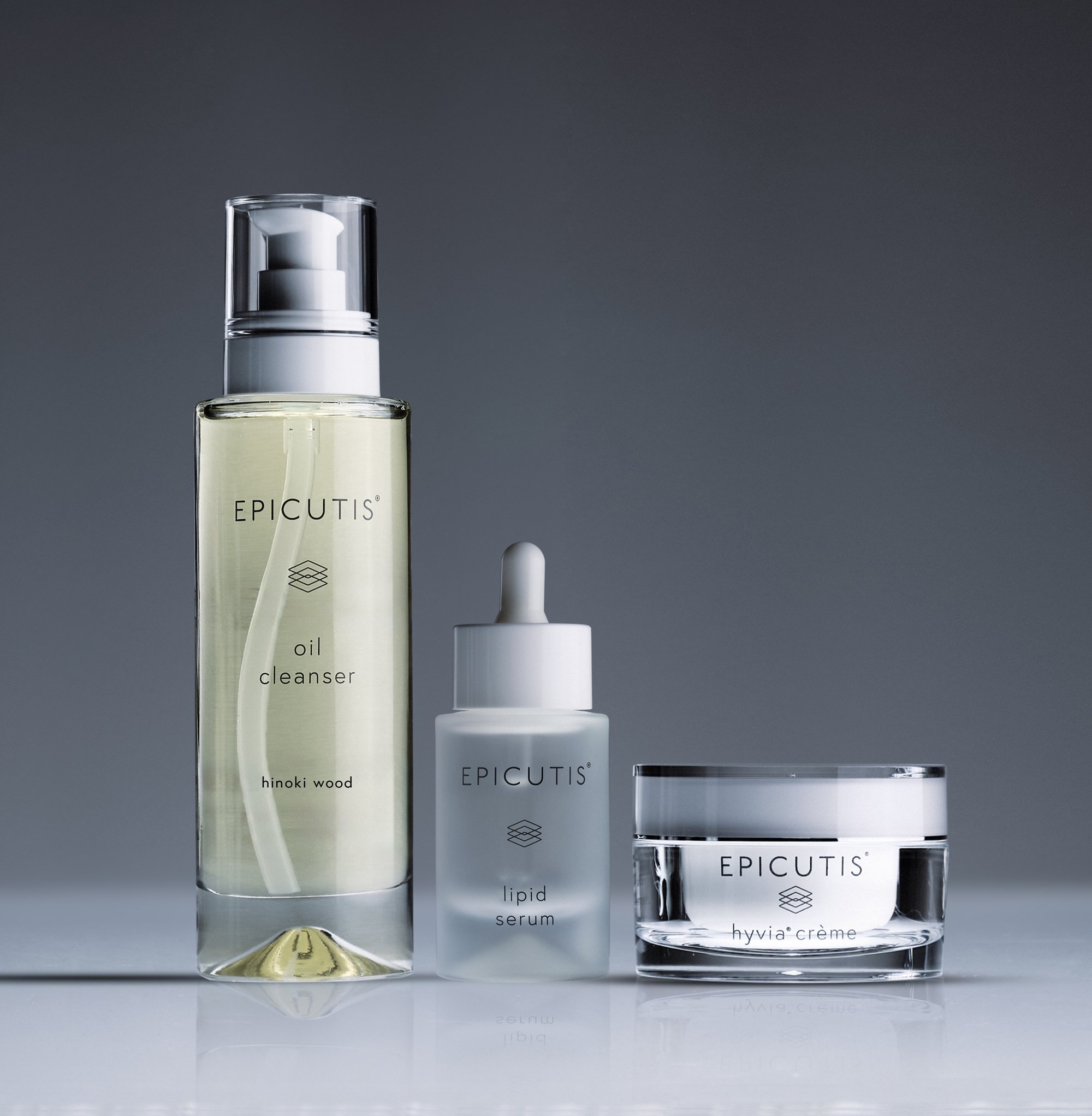 A collection of skincare products including a tall bottle labeled 'epicutis' with a pump, a smaller bottle labeled 'lipid serum', and a jar labeled 'hyvia crème', all against a gray background.