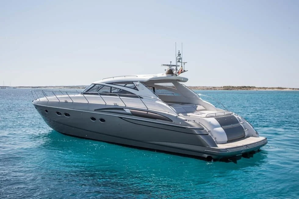 A luxury yacht floating on calm blue water with a clear sky and a distant shoreline in the background.