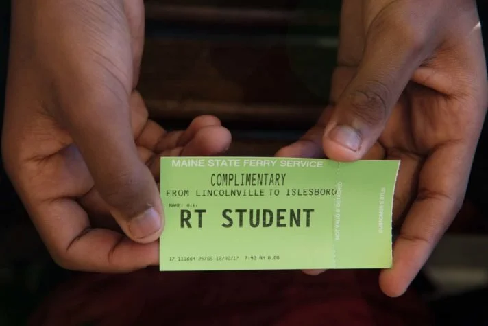 Person holding a green Maine State Ferry Service complimentary ticket from Lincolnville to Islesboro for RT Student.