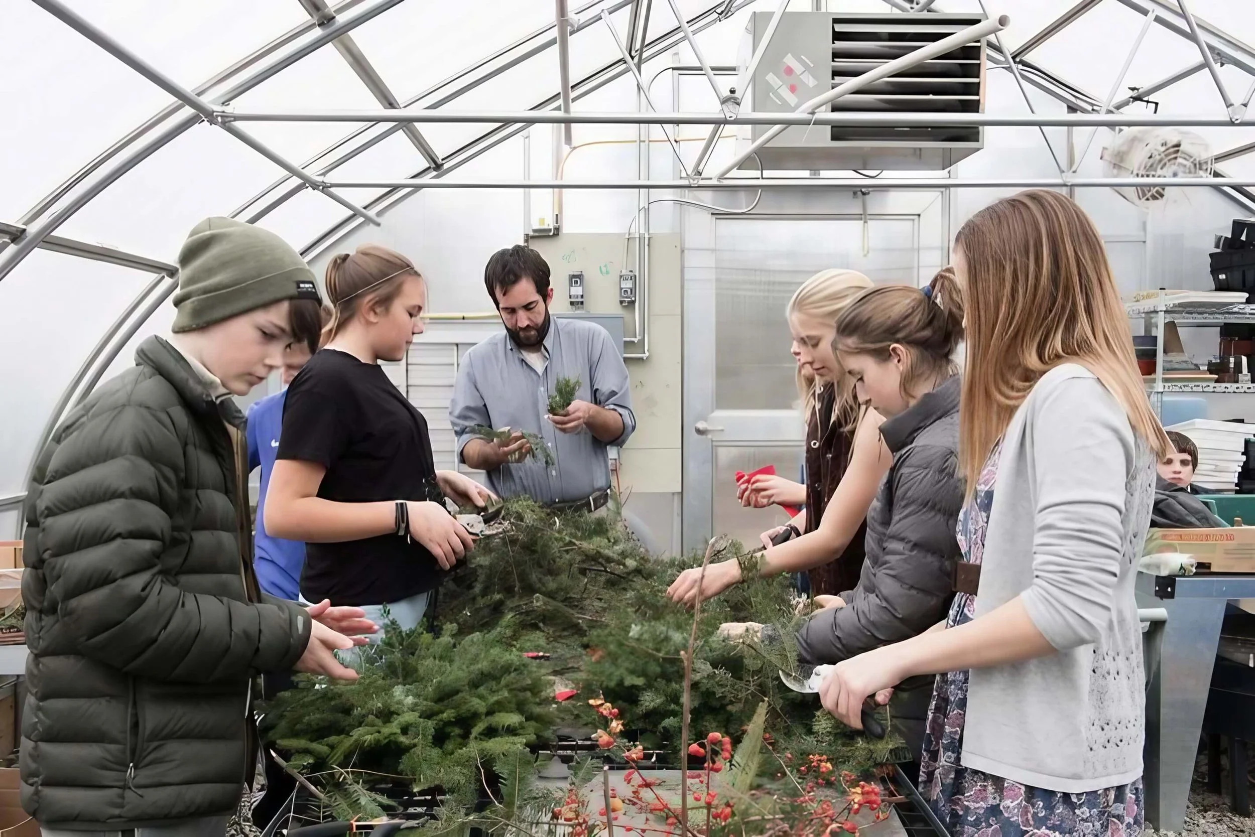 Group of people in a greenhouse working with plants and flowers.