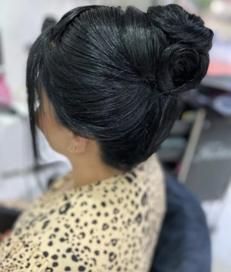 Woman with intricately styled updo hairdo, wearing a leopard print garment.