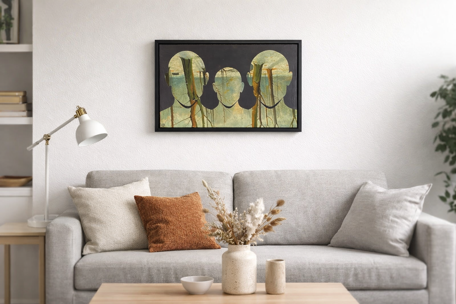 Woonkamer met lichtgrijze bank, decoratieve kussens, een plank met boeken, een witte bureaulamp, een tafel met vazen en een schilderij van mensen met gezichten bedekt met boomringen, witte muren en een groene plant.