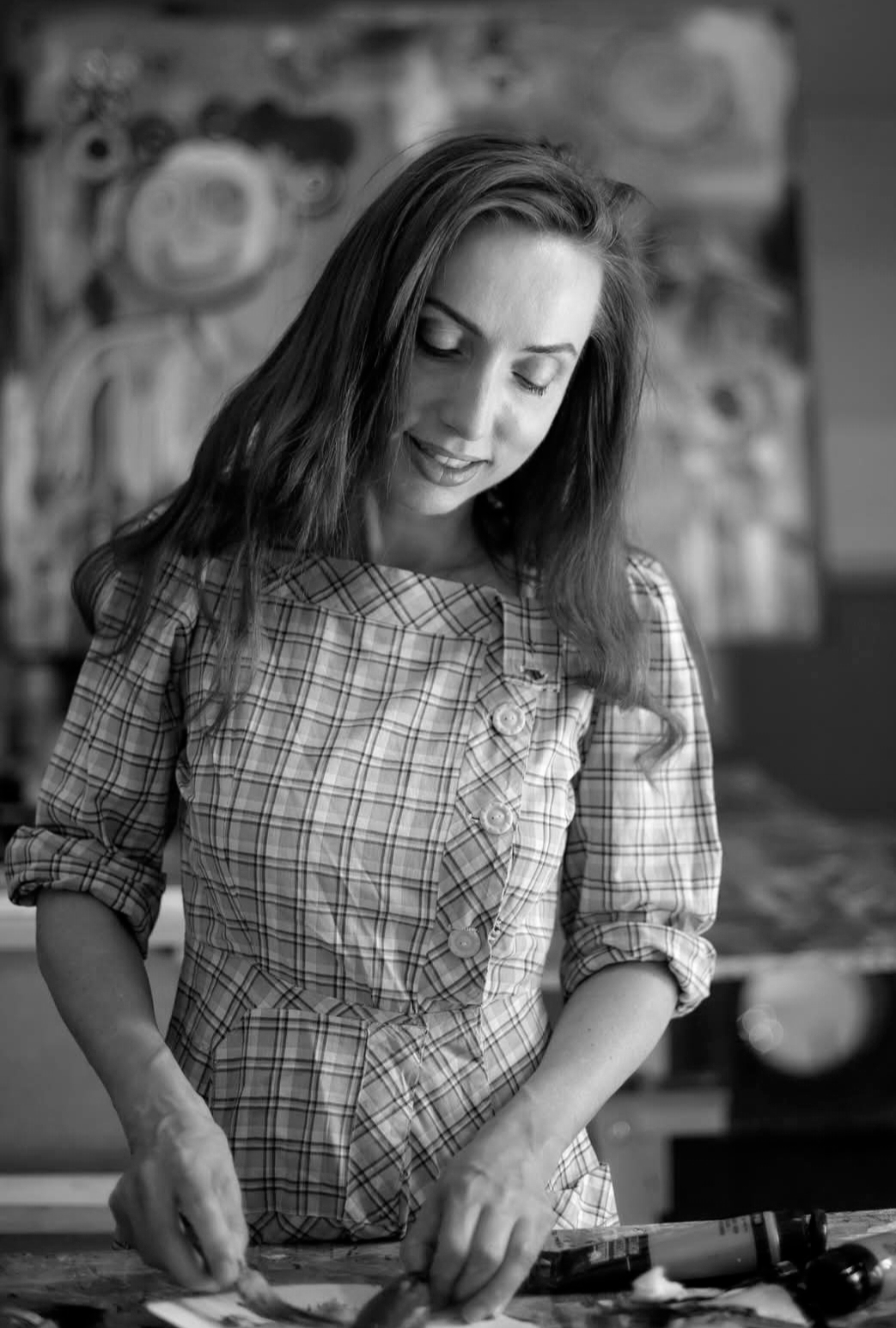 een vrouw met bruin haar die een lapje kleding draait in een keuken, gekleed in een geruite blouse.