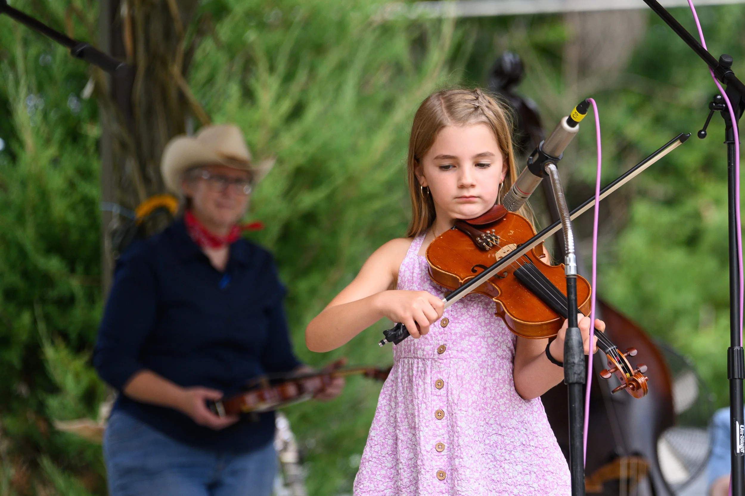 Young girl fiddler in forreground, blurry older man fiddler in background