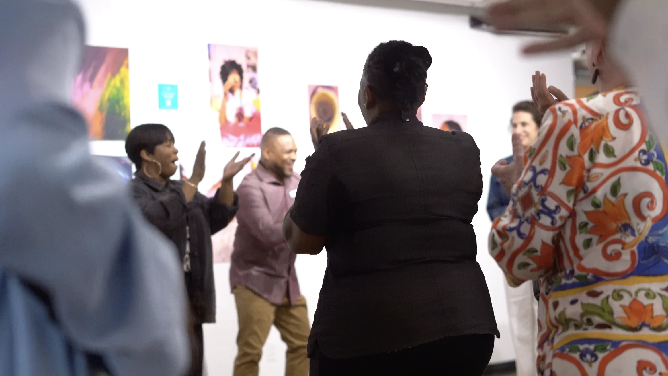 Group of people standing in a circle with art on the wall, engaging in conversation or an activity.