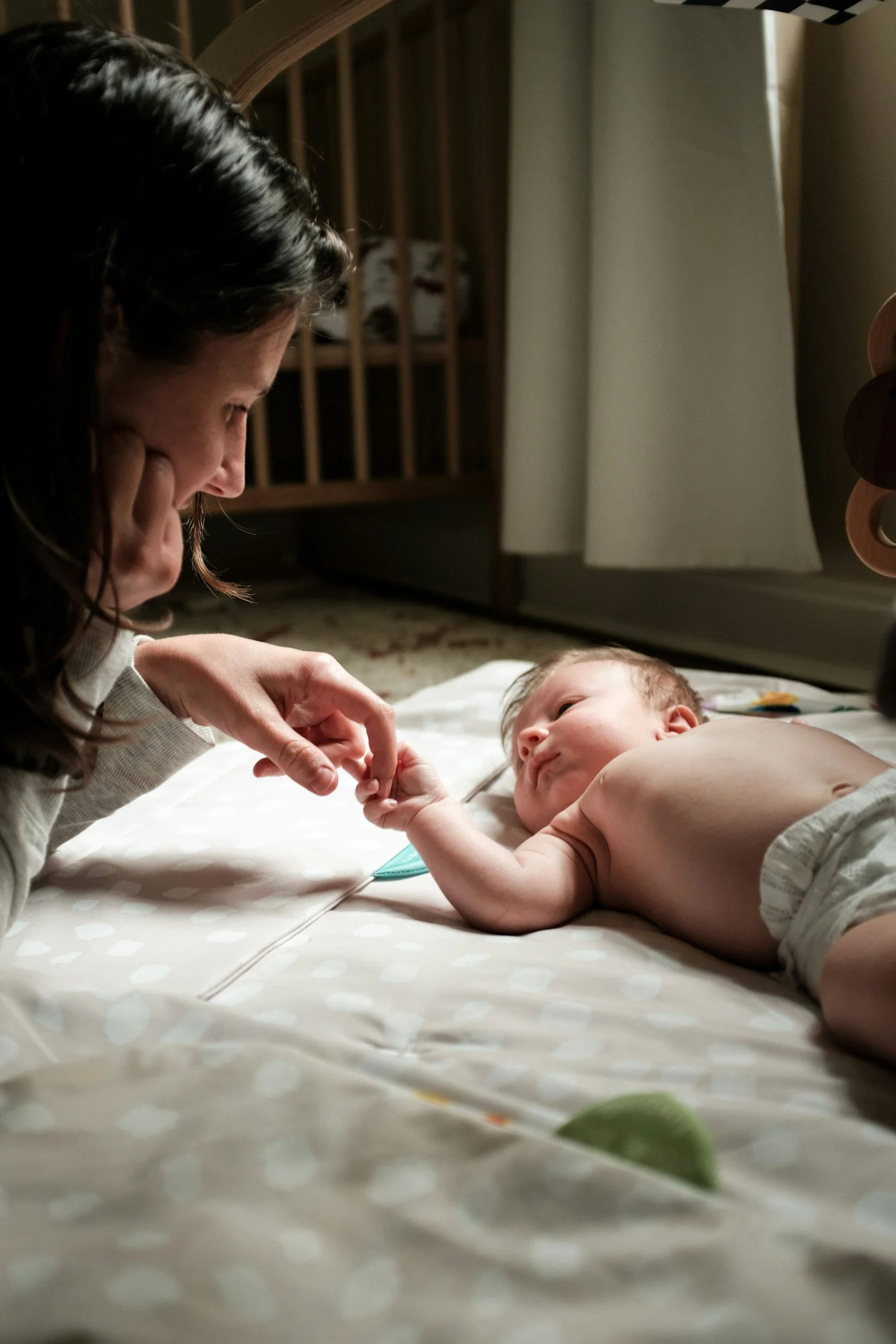 An occupational therapist engaging with an infant laying on the ground.