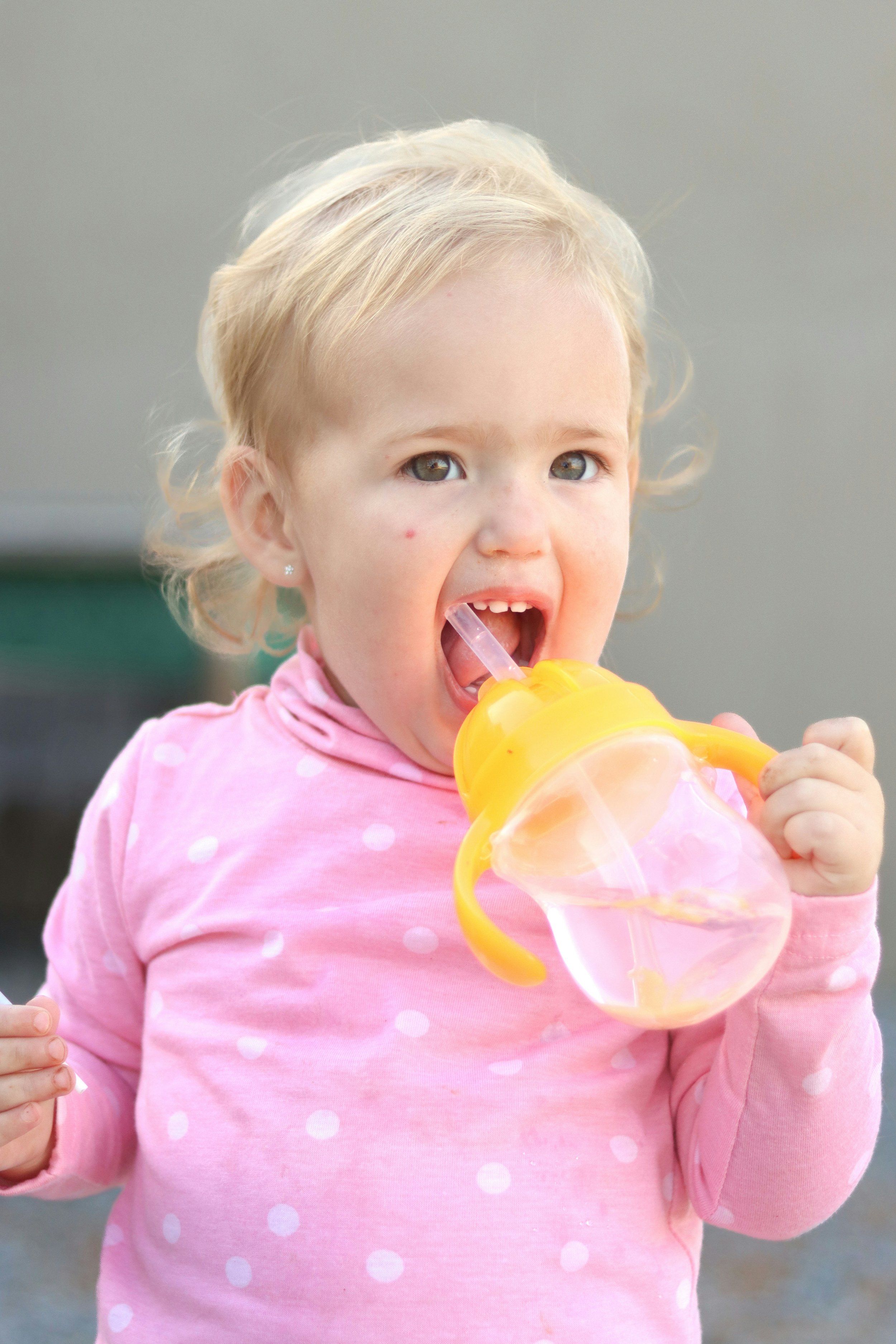 toddler learning how to drinking from a straw cup