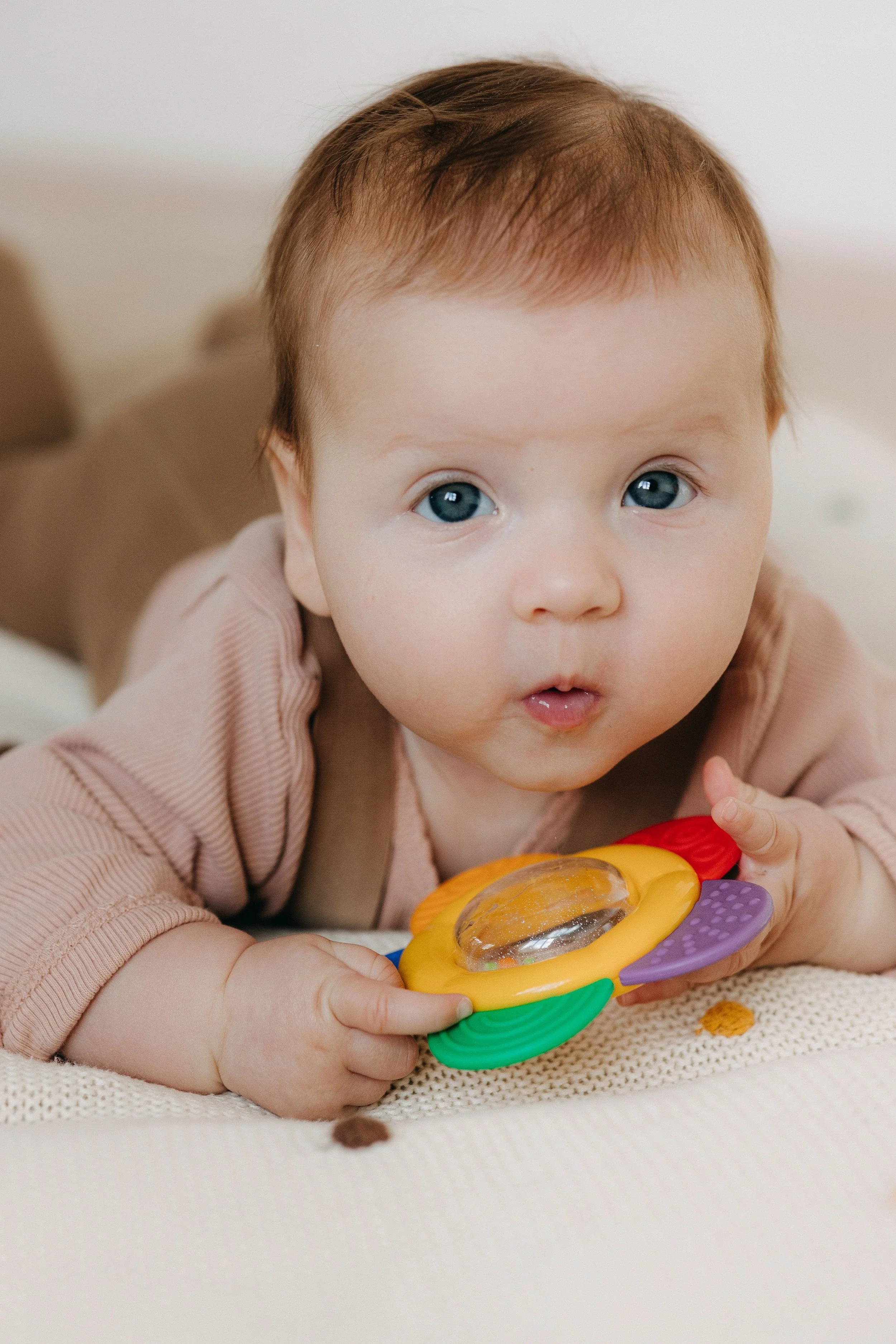 A baby lifting his head up and looking at his mom during a session of the Tummy Time! Method