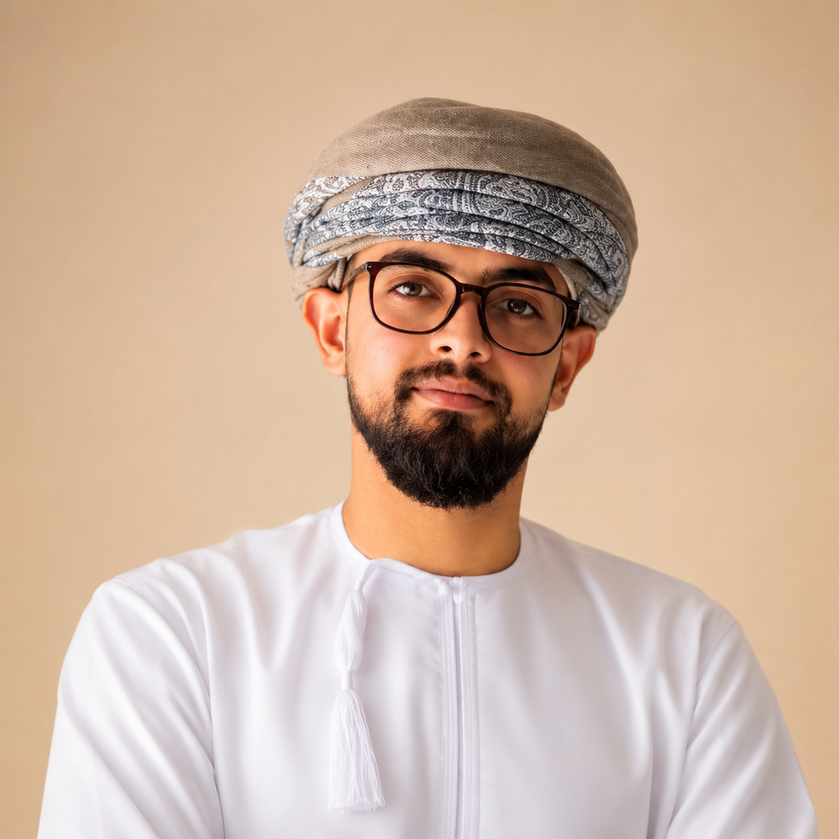 A man with glasses, a beard, and a mustache wearing a white traditional Omani dishdasha and a turban, standing against a beige background. GM btw Ironman btw Challenger btw twitch main btw nissan Z btw nissan VTC btw