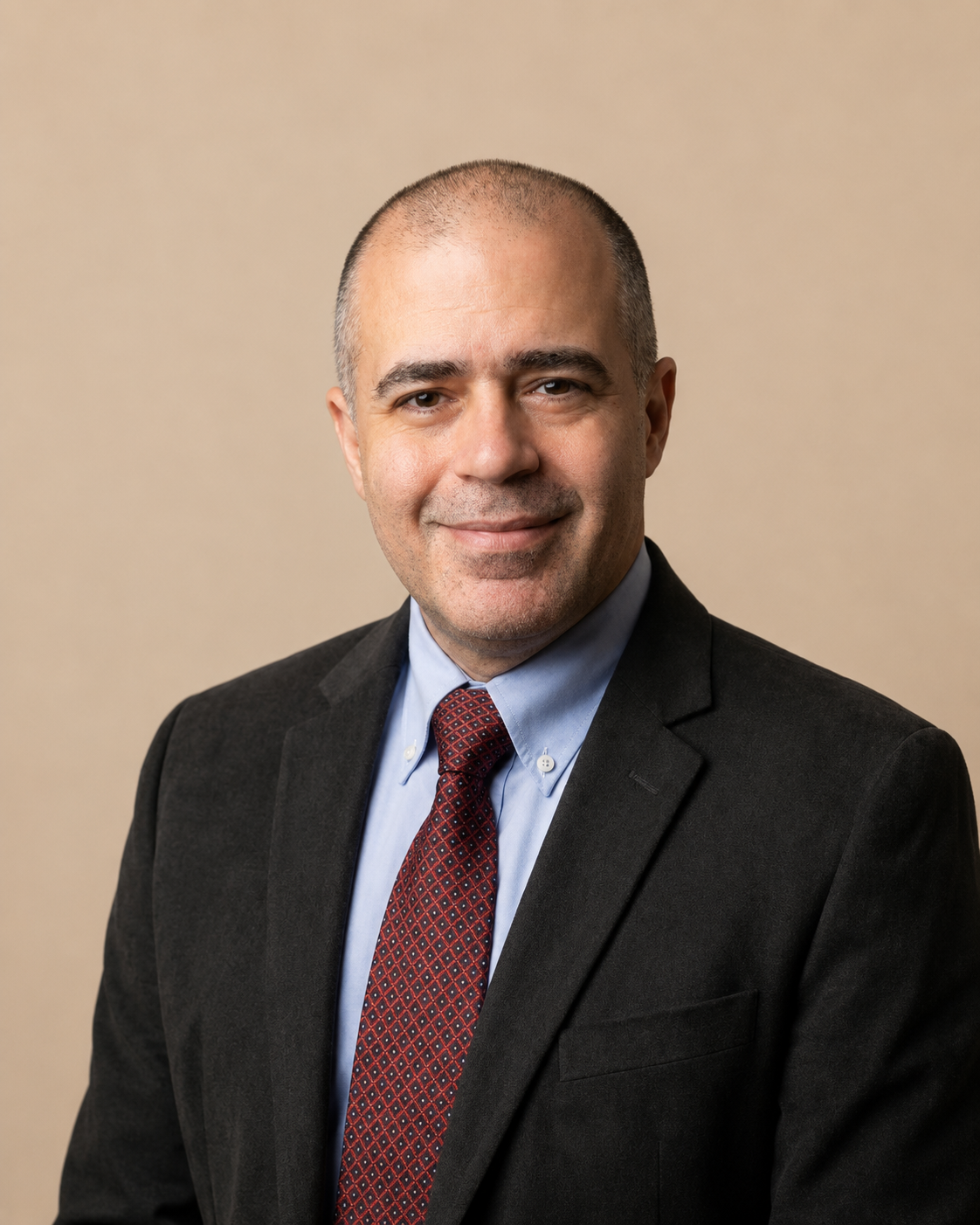 A professional man in a suit and tie posing against a plain background.