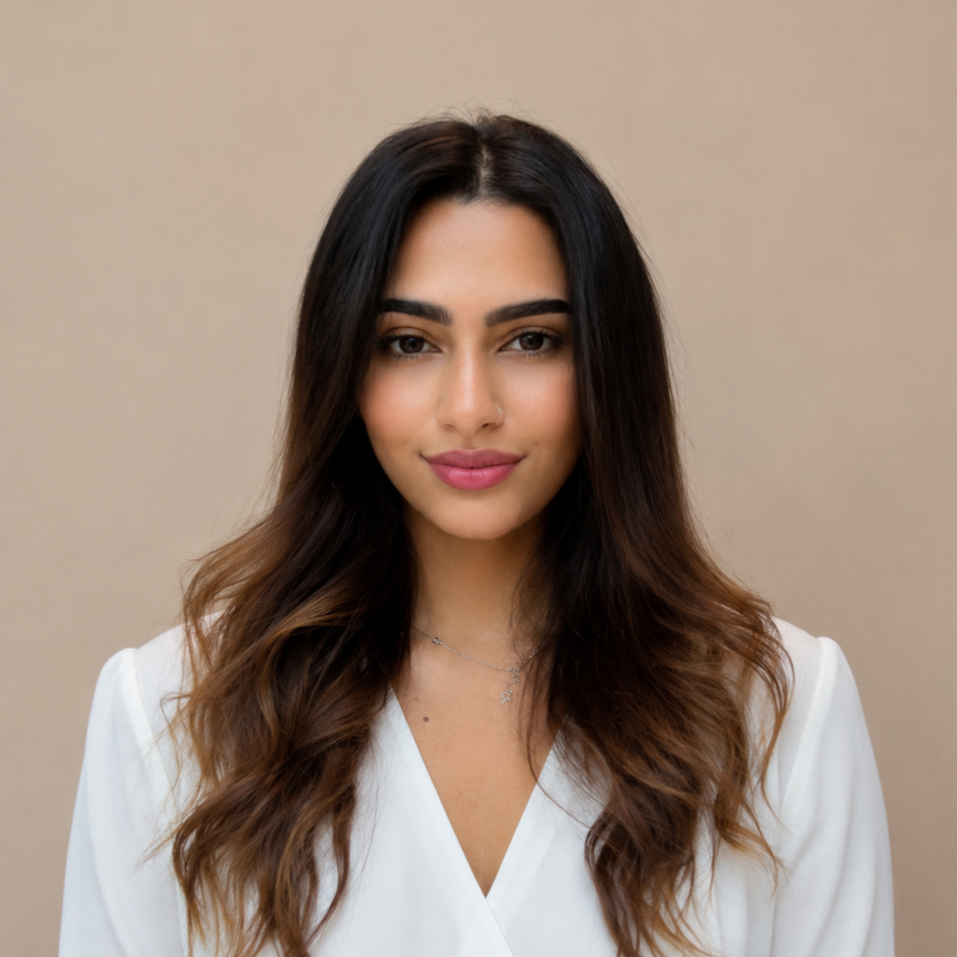 Young woman with long dark hair and light skin, wearing a white top and a delicate necklace, looking confidently at the camera against a plain beige background. Hotelier btw Chef btw