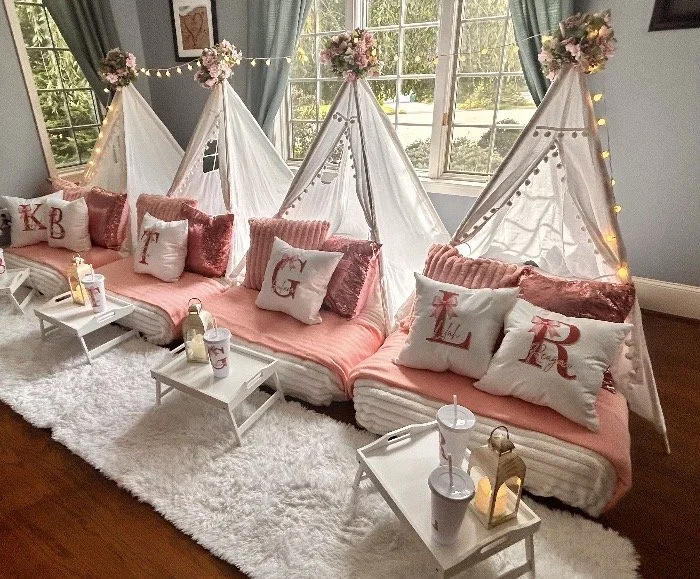 Pink floral luxury teepee sleepover party with personalized pillows, white tents, pink bedding and twinkle lights in Connecticut.
