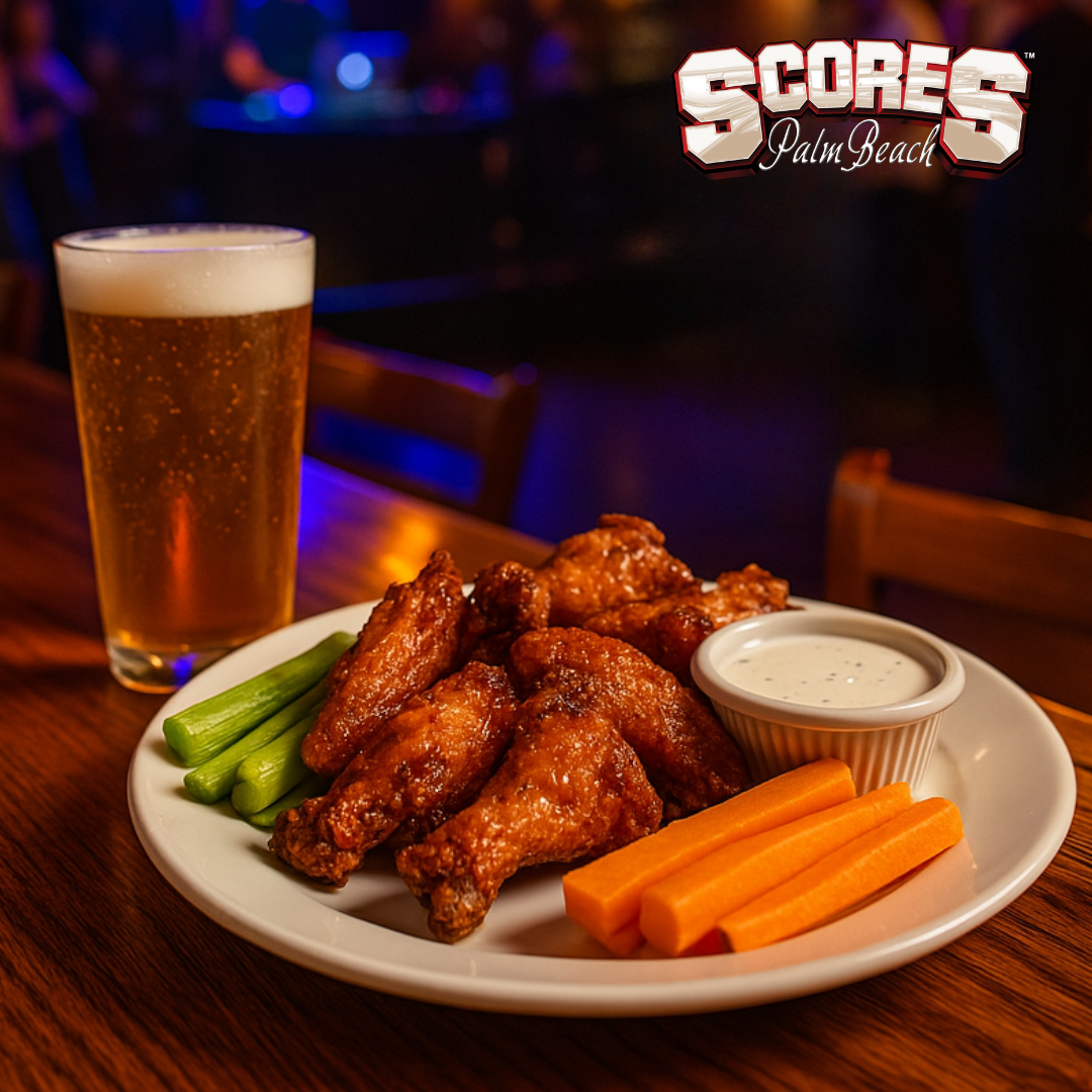 Crispy chicken wings with carrots, celery, ranch dip, and beer served at Scores Palm Beach bar