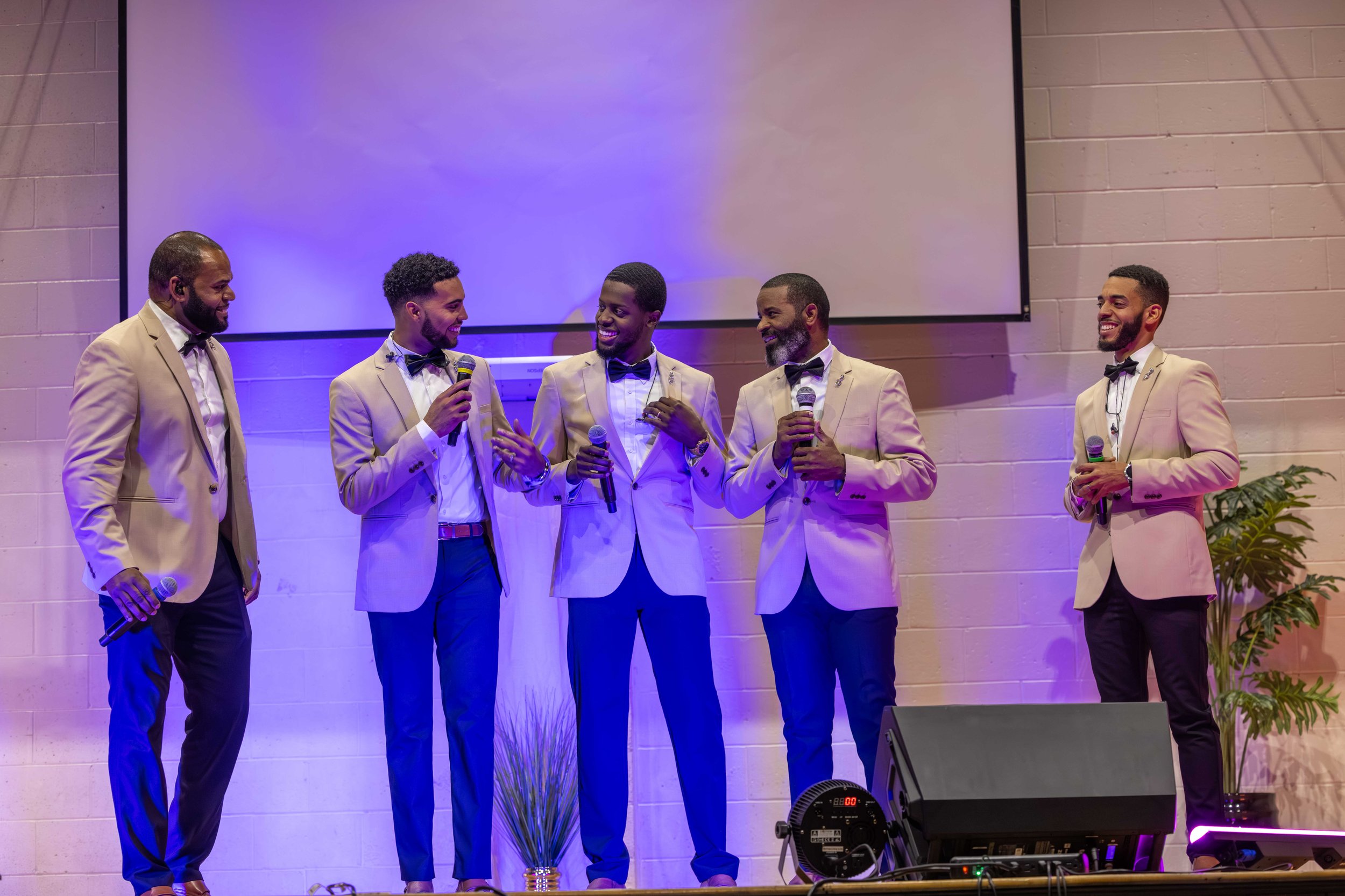 Six men dressed in beige suits and black bow ties are standing on stage, holding microphones, and engaging in conversation. They are smiling and appear to be enjoying a presentation or event.
Heralds of freedom 5th annual concert.
