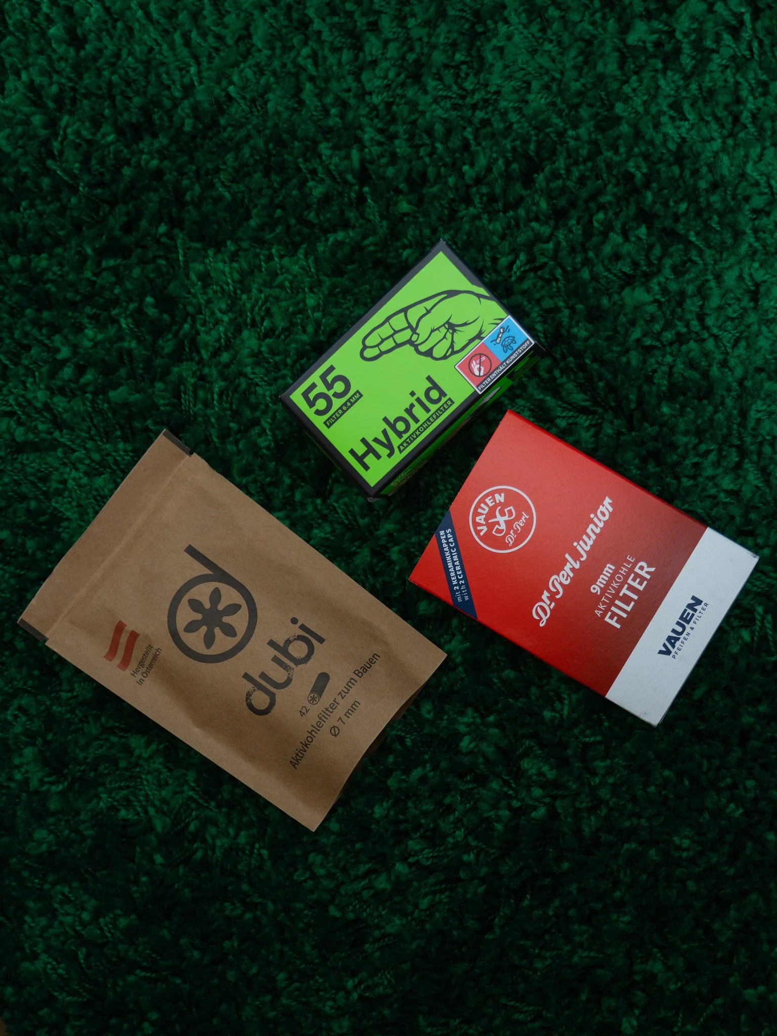 Assorted cigarette filters and packaging on green textured surface.
