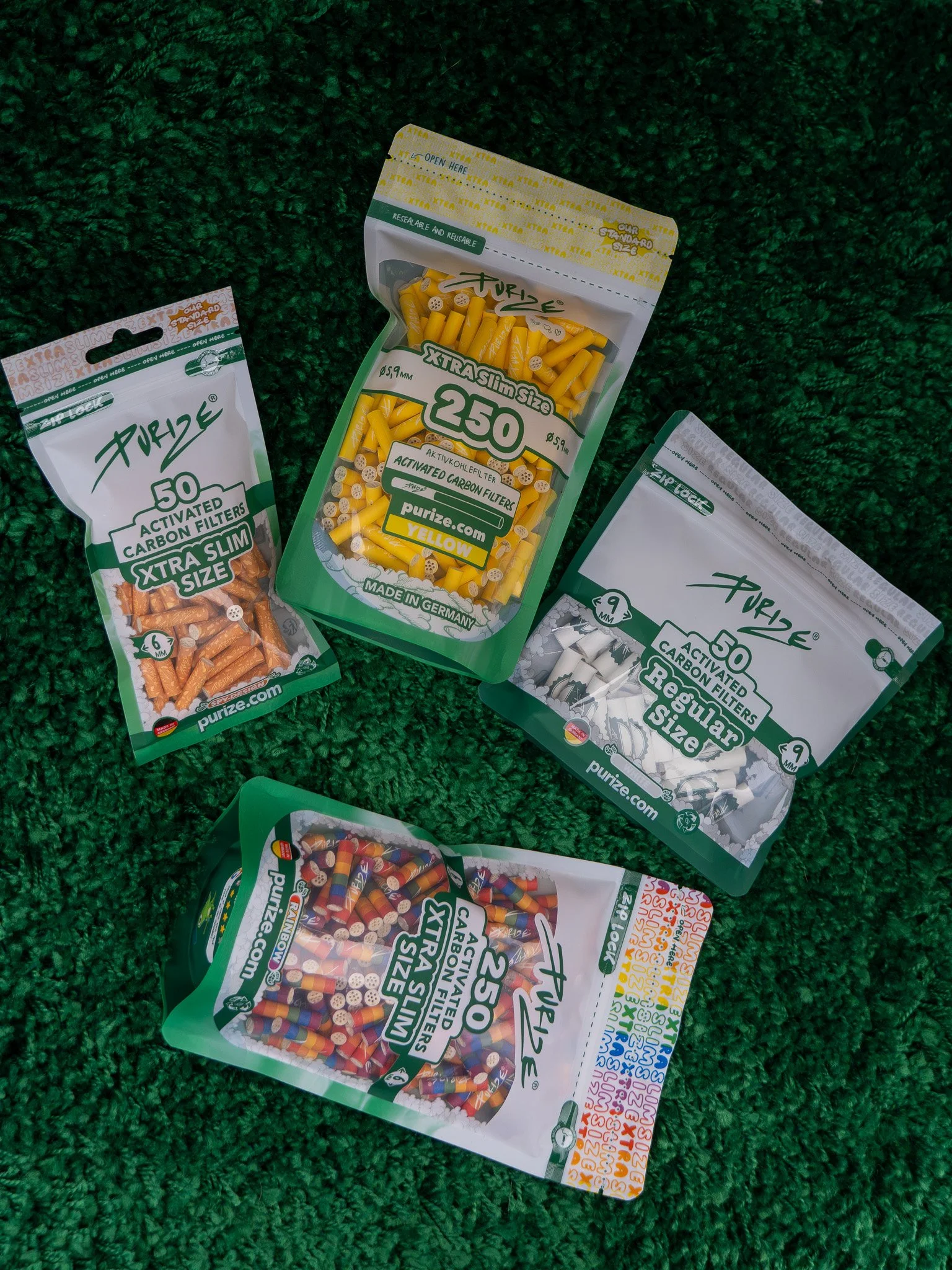 Multiple packs of activated carbon filters for air purifiers with colorful designs, laid out on a green textured surface.