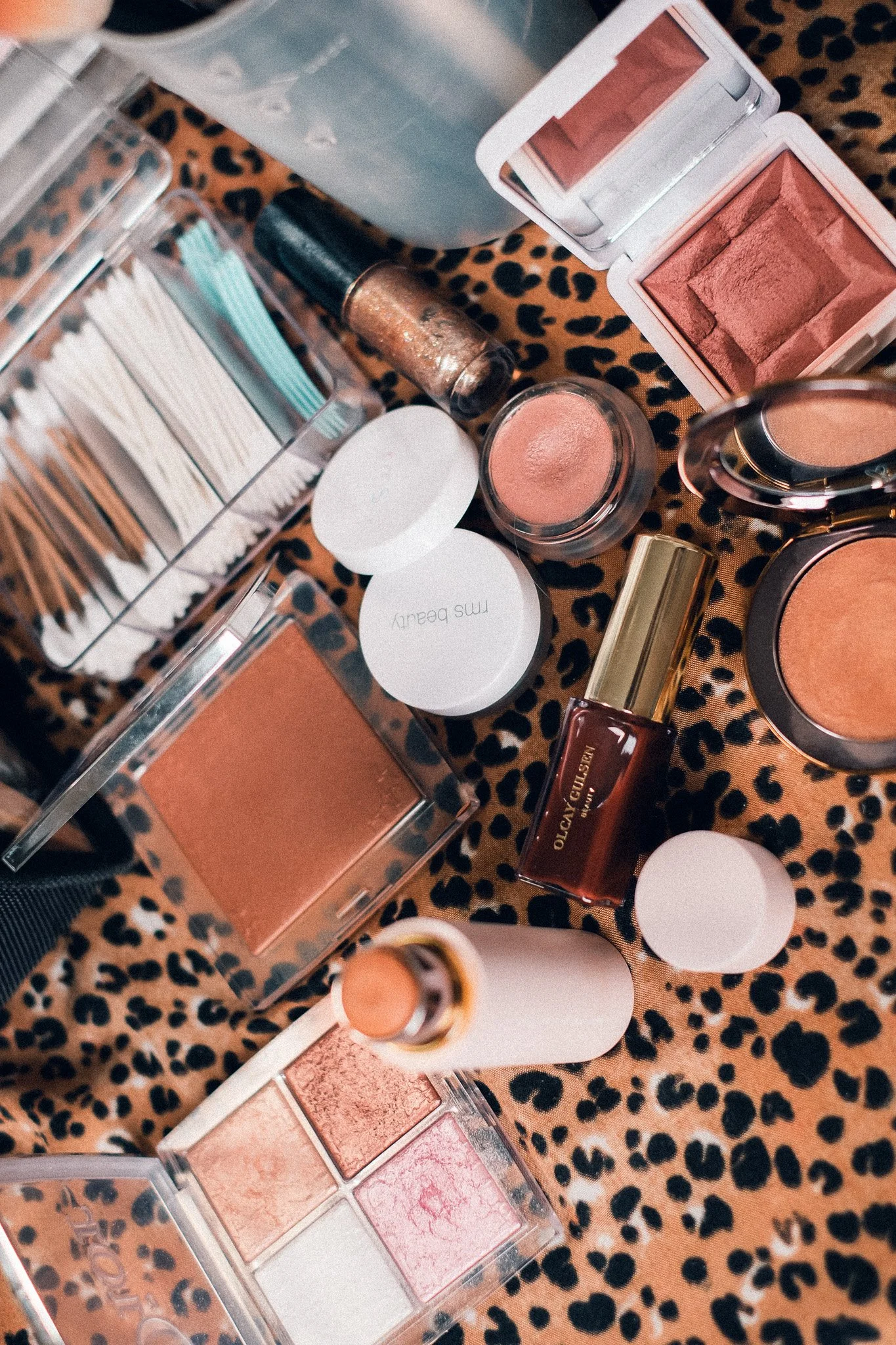 Various makeup products including eyeshadows, blushes, and brushes on a leopard print surface.