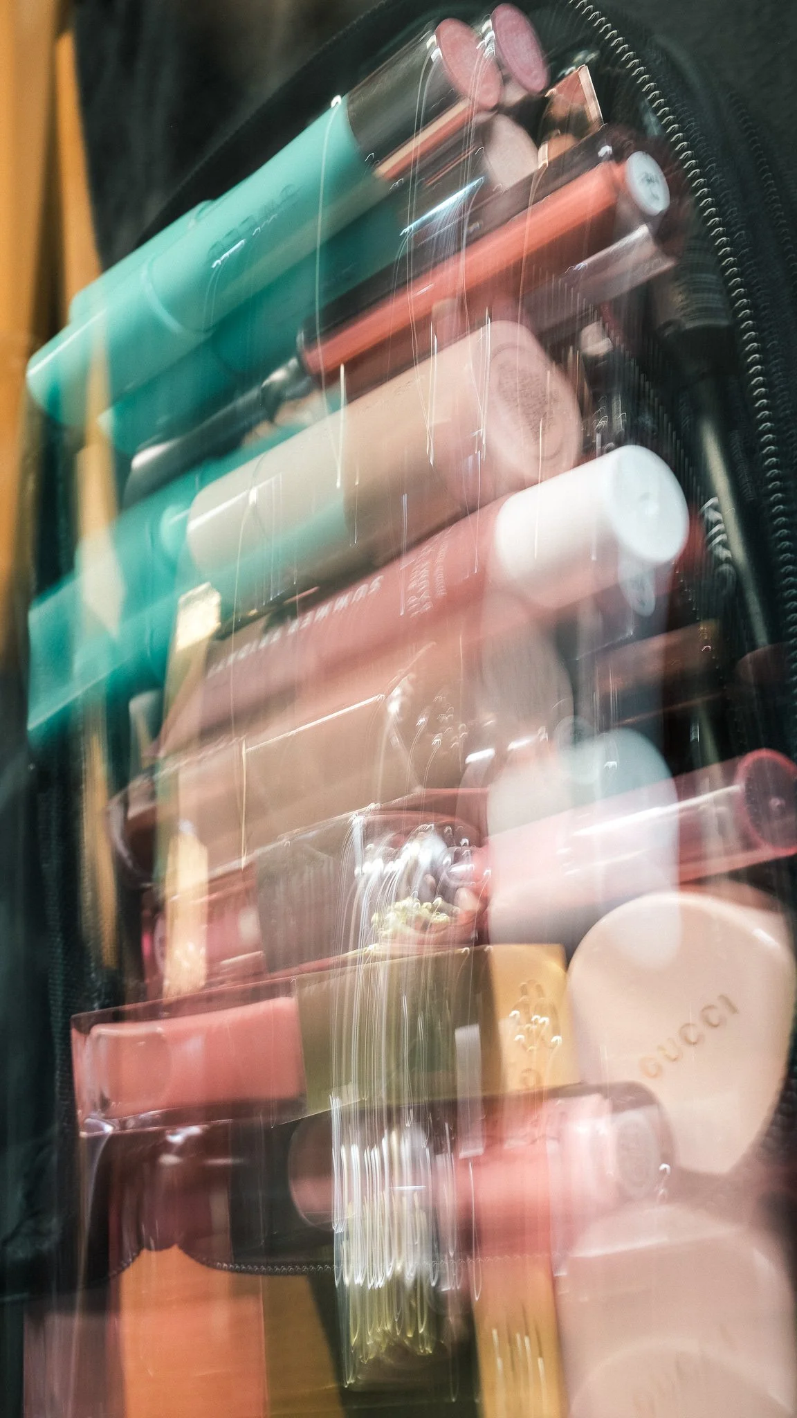A blurry photograph of various colorful makeup products inside a transparent bag.