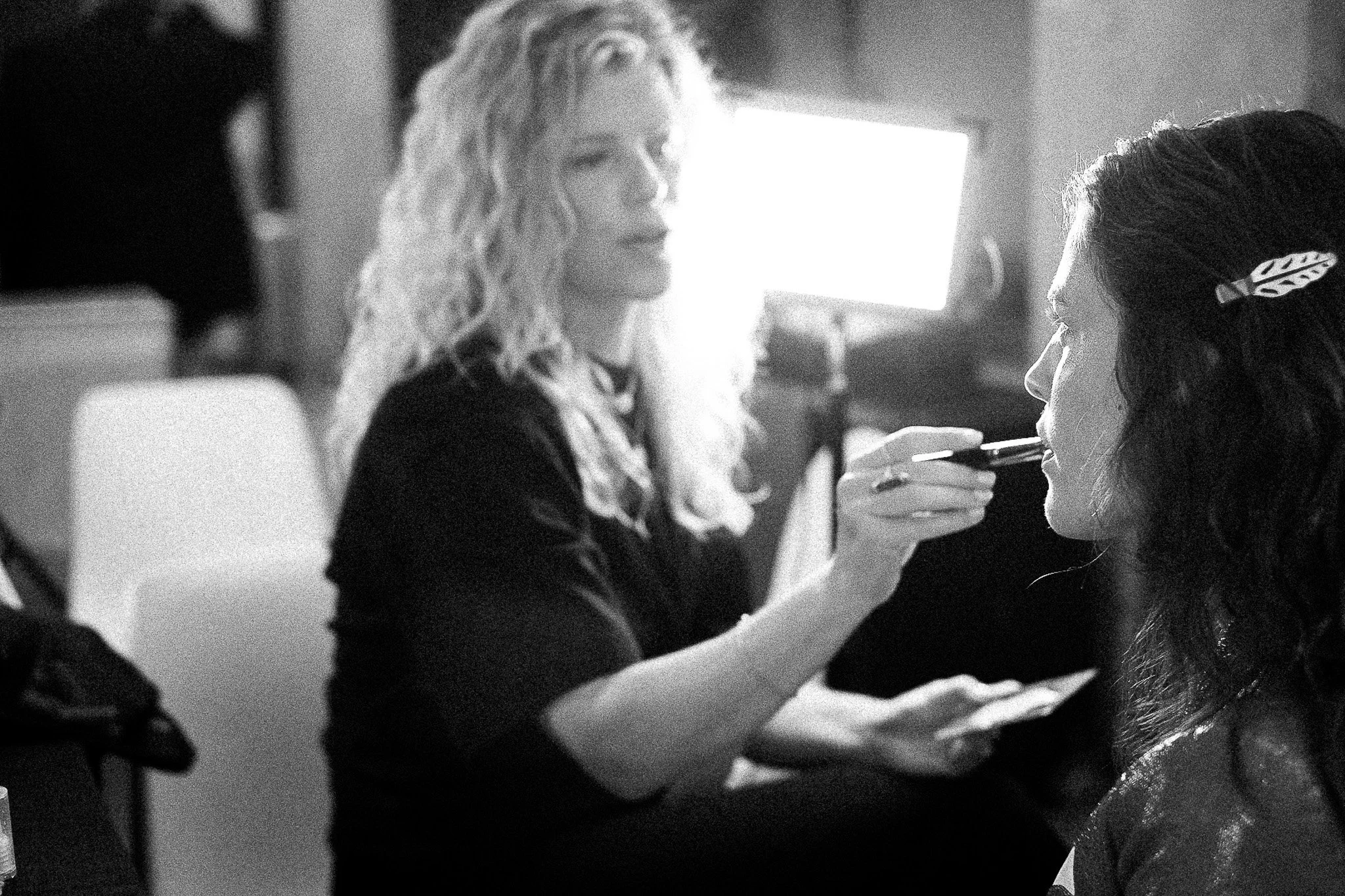 A woman receiving makeup application from a makeup artist in a professional setting.