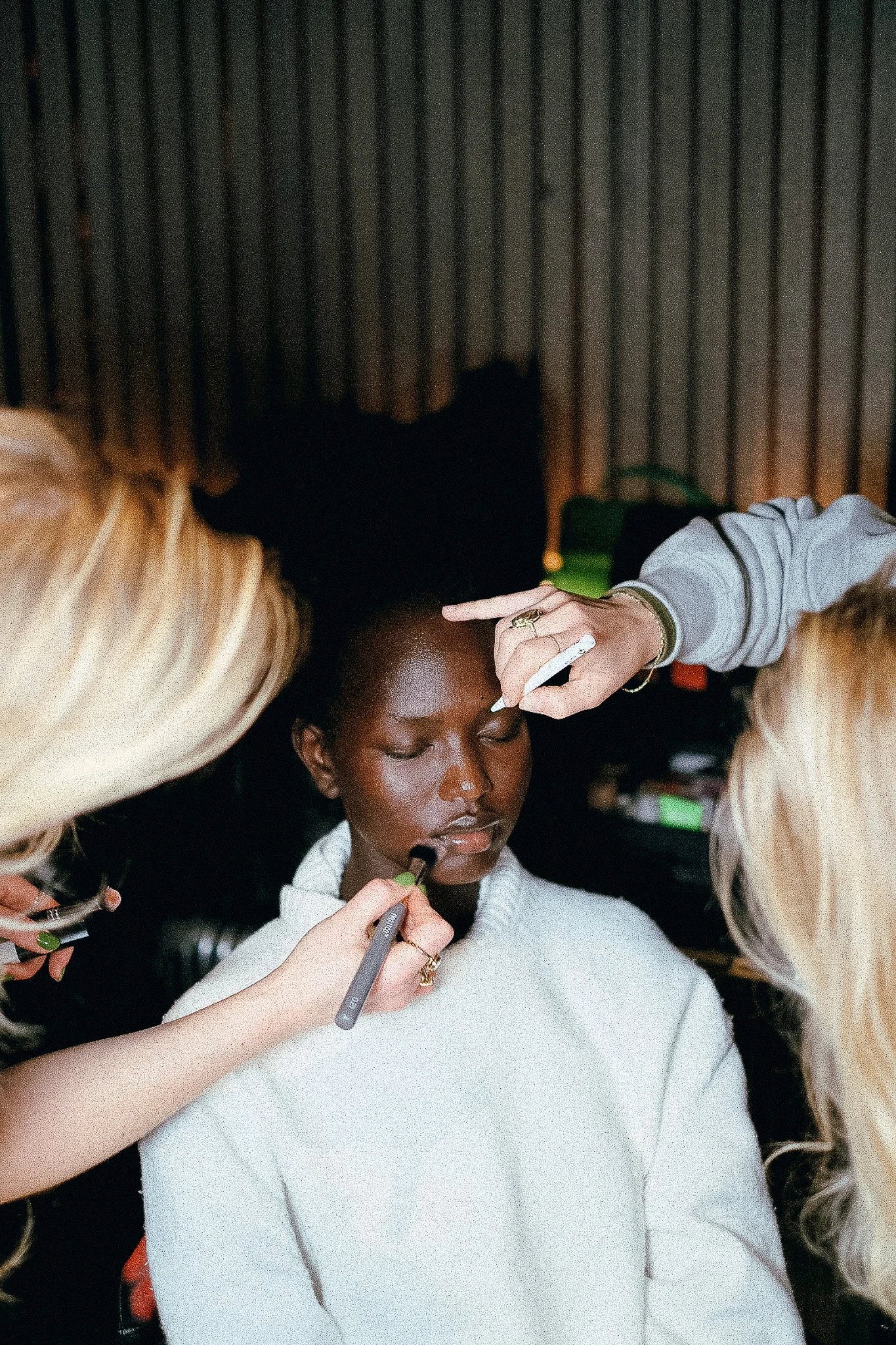 A woman is having makeup applied by a makeup artist at a salon or makeup studio.