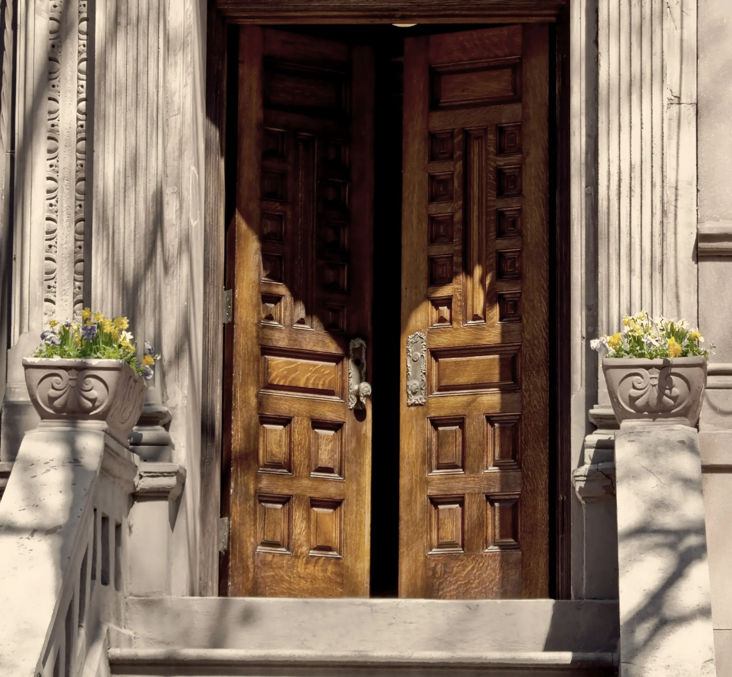 Partially open carved wood doors at the entrance of a classic Brooklyn townhouse with original architectural details