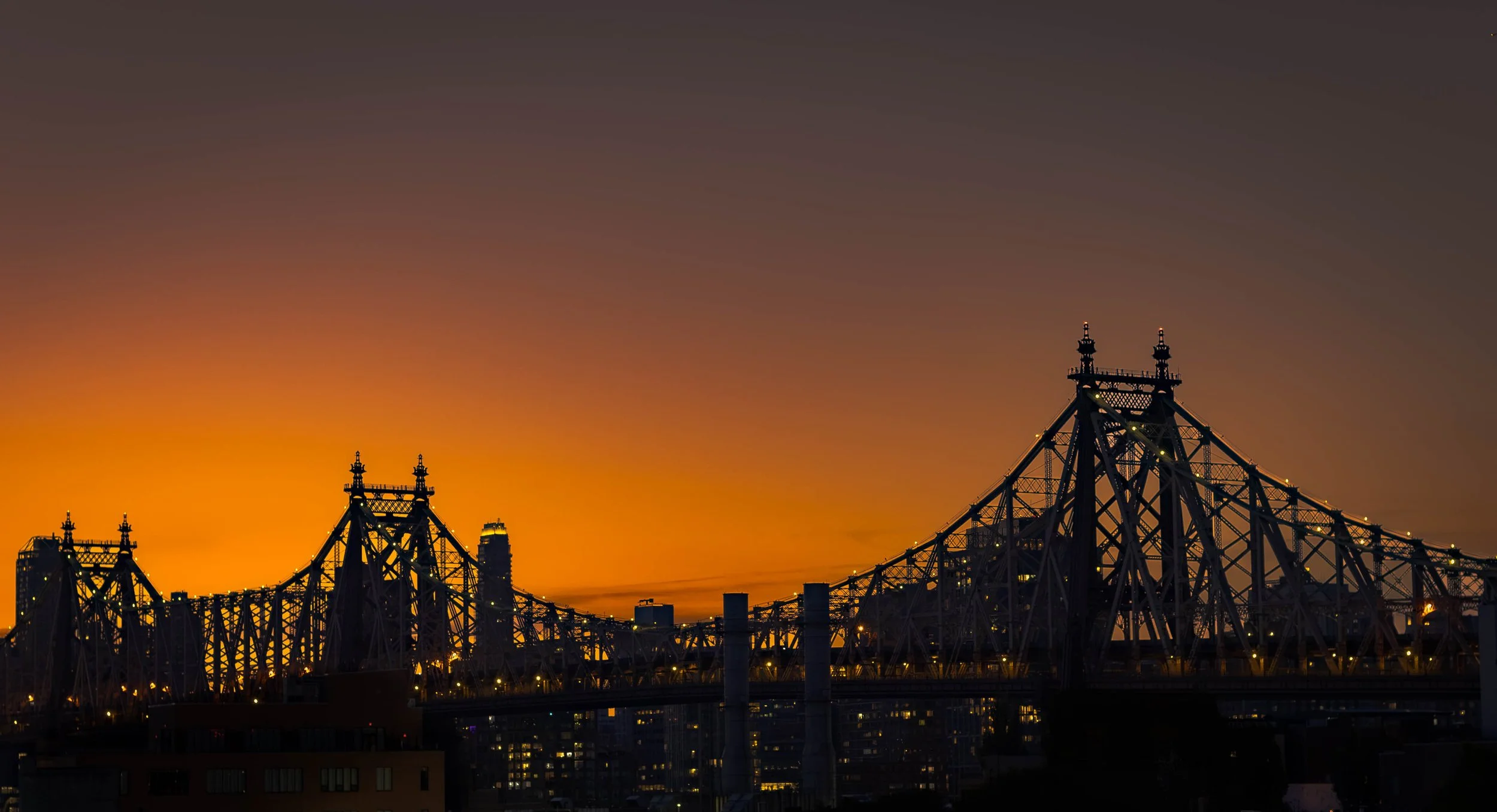 A wide sunset shot of the Queensboro bridge from afar.
