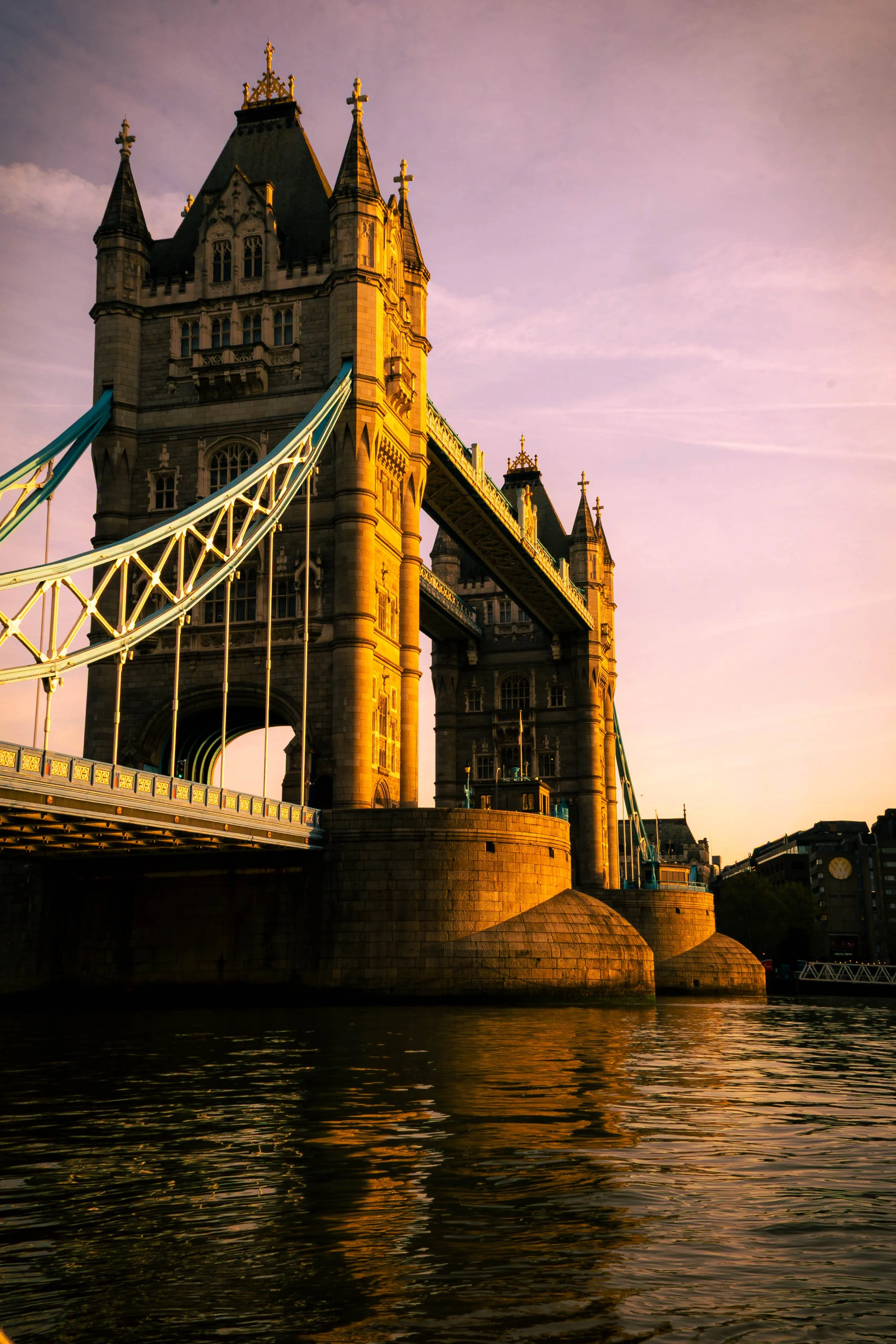 The Tower Bridge in London during sunset with a pink sky reflected in the river.