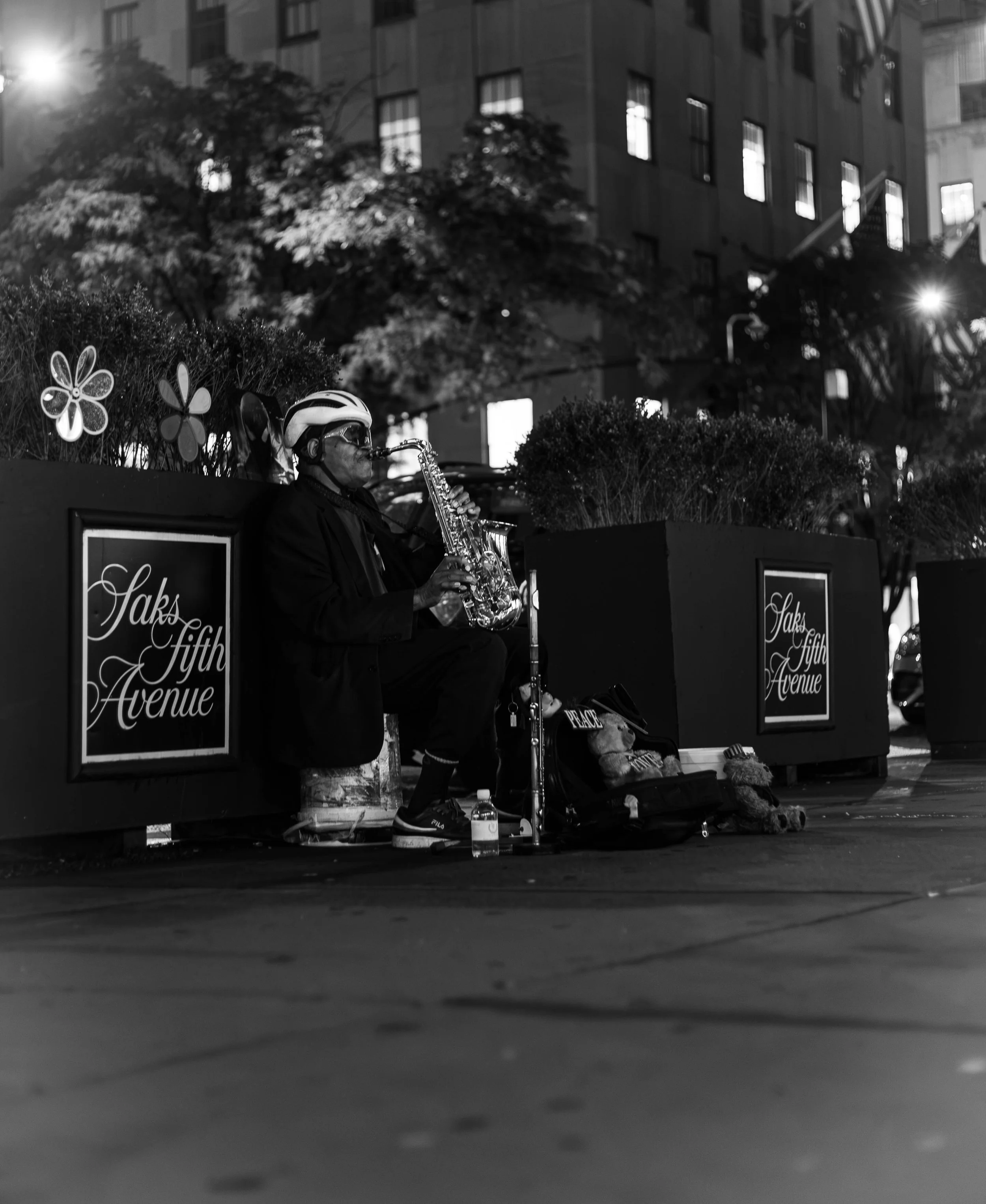 A dude playing jazz music at night on 5th ave in NYC.