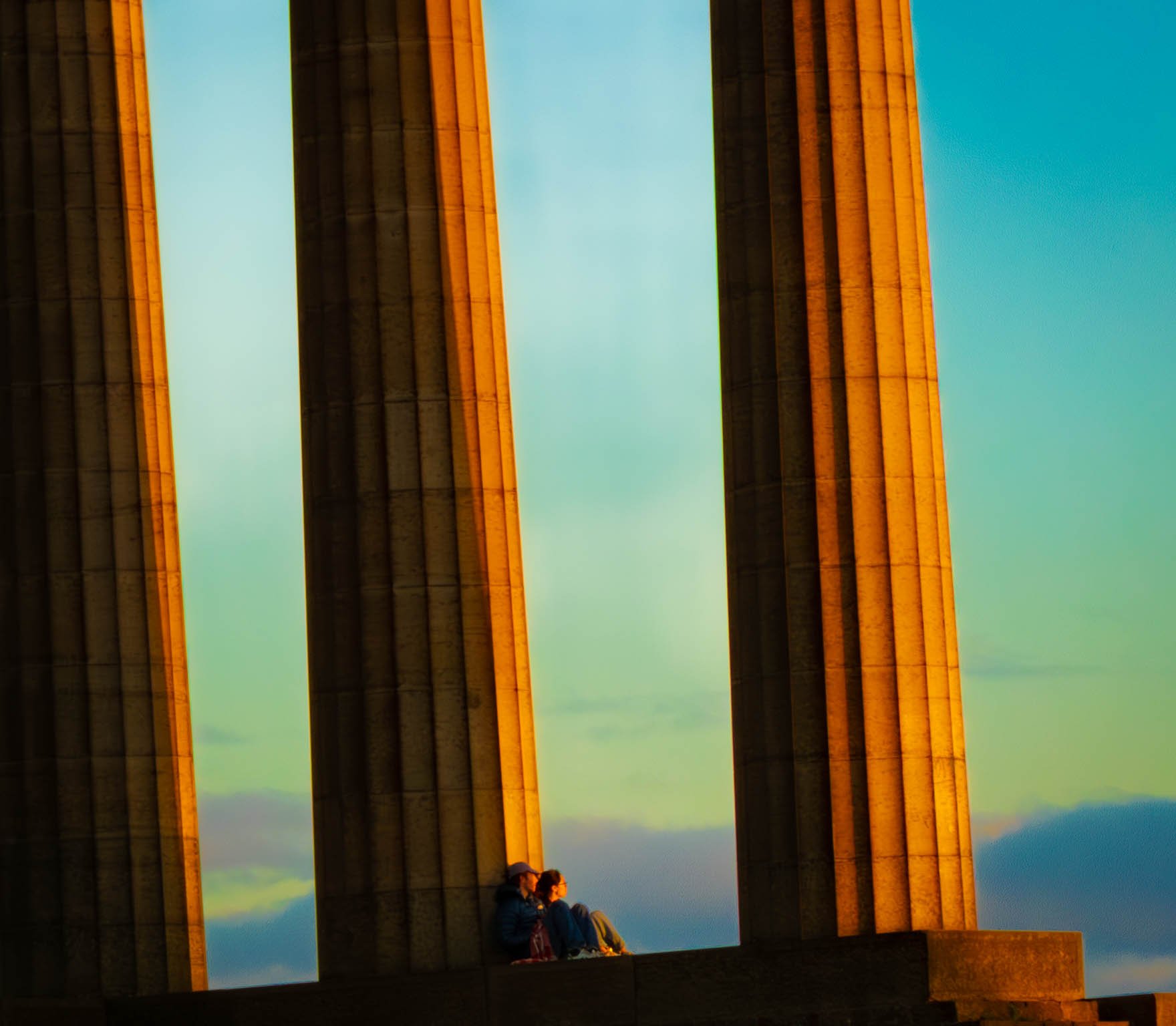 A couple sitting up on an old roman structure just enjoying the sunrise.