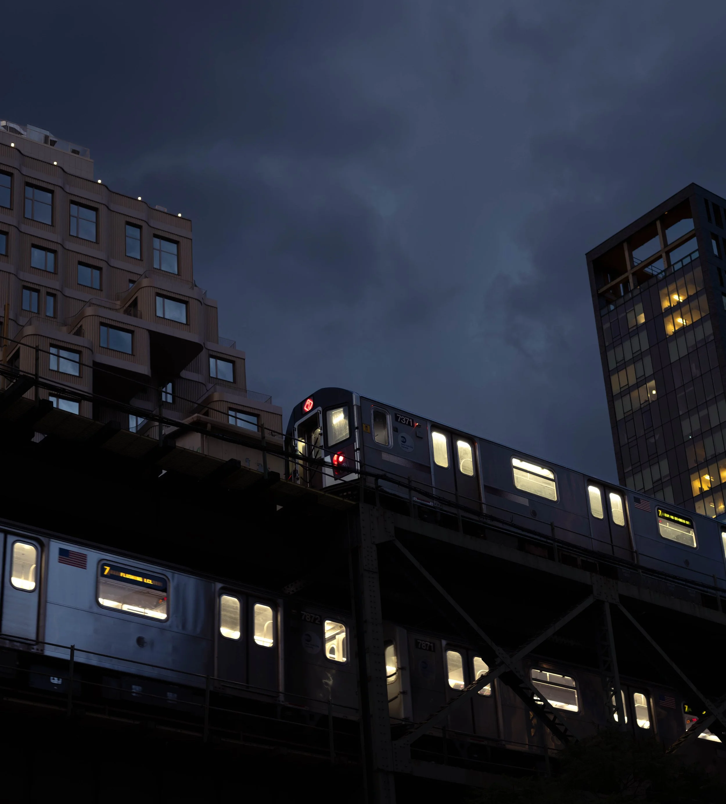 A moody night shot of two 7 line trains passing by each other in queens plaza.