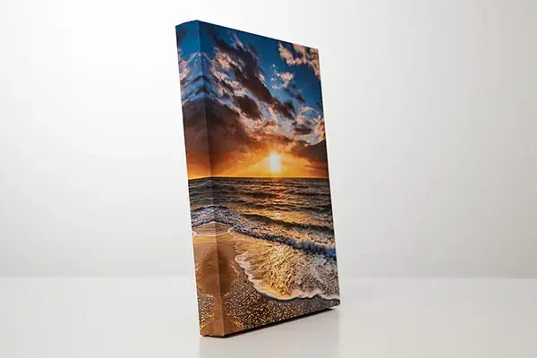 A vertical canvas print featuring a sunset over the ocean with waves and a partly cloudy sky.