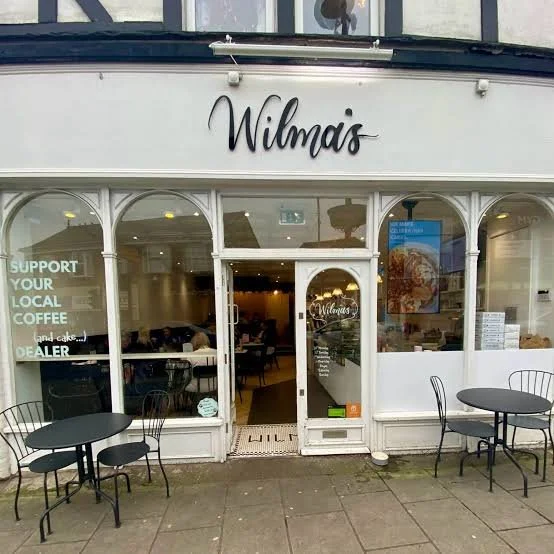Exterior of Wilma's café with outdoor tables, windows, and visible interior seating