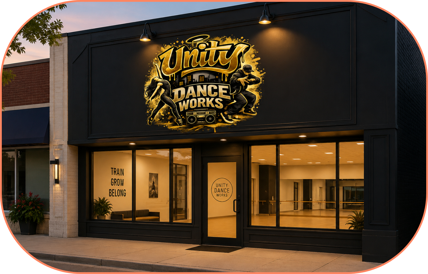 Exterior of a dance studio with a large sign reading "Unity Dance Works" featuring silhouettes of a dancer and a breakdancer, a boombox, and a cityscape background, with a glass door and windows showing the interior studio.