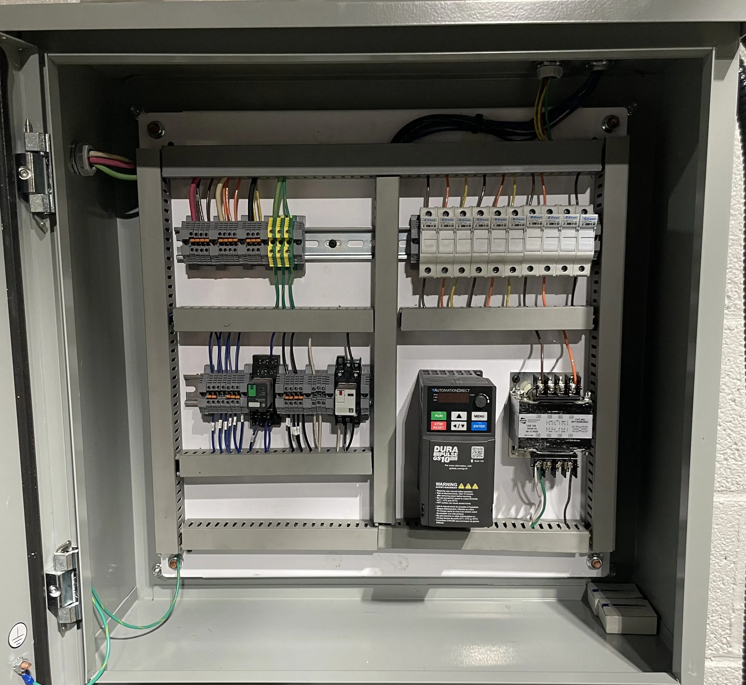 Open electrical control panel with wires, circuit breakers, and digital controller inside.