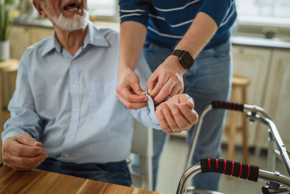 A carer helping an older man get dressed at home