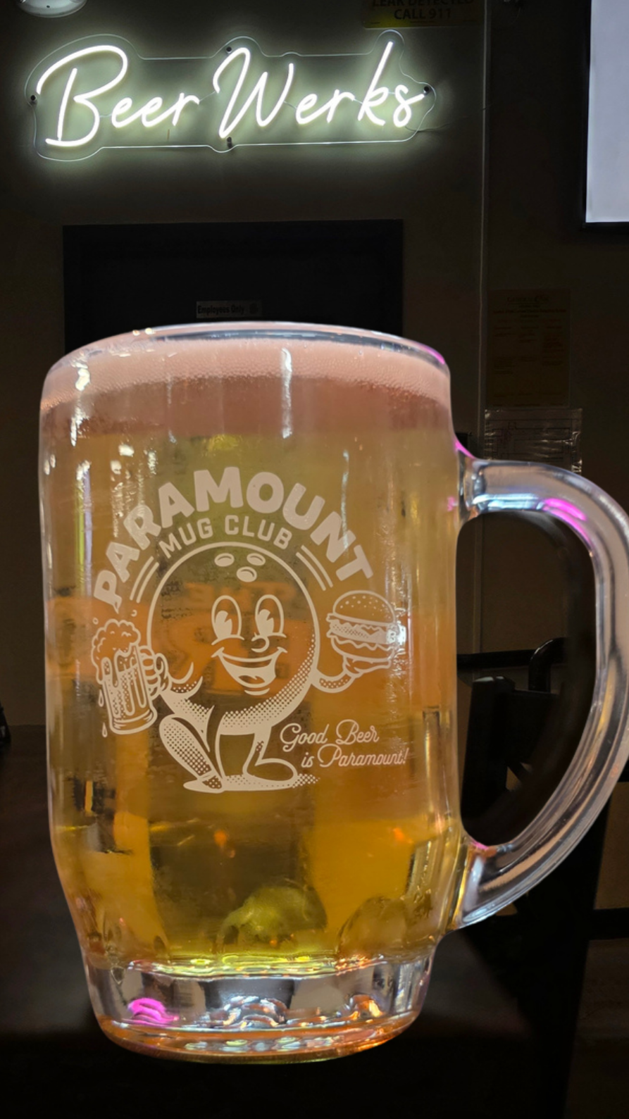 Paramount Mug Club stein filled with pale golden Manny’s Wey beneath the glowing BeerWerks sign.