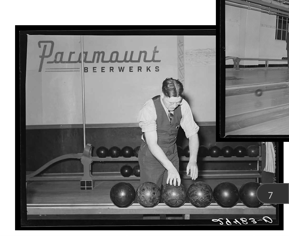 A woman arranging bowling balls on a rack in a bowling alley with a sign that says 'Paramount Beerwerks' in the background.
