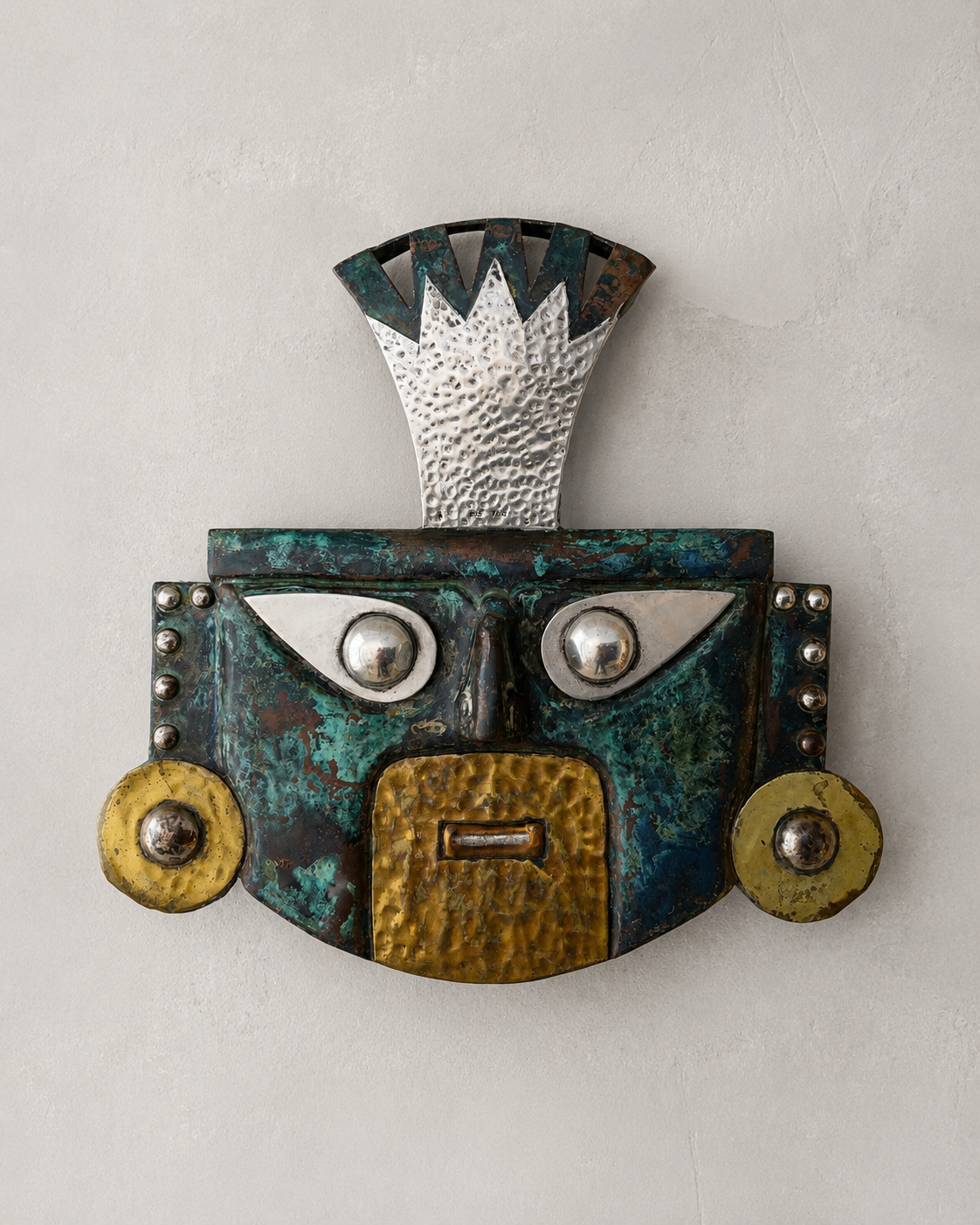 Funerary mask with a richly patinated finish, featuring a silver crown stamped "925 PERU". Such masks with characteristic ovoid eyes terminating in a point are associated with the Lambayeque culture named for a region near the modern city of Chiclayo