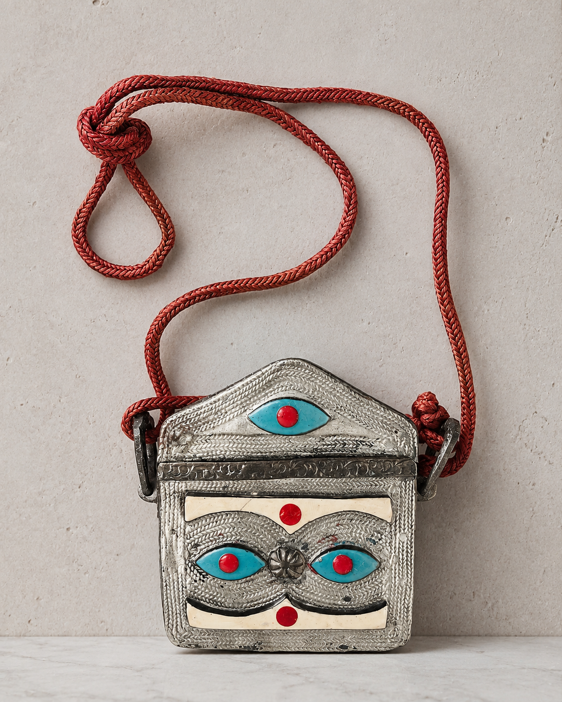 Traditional Moroccan Qur'an amulet holder with coloured inlay and woven cord. Such boxes were designed to hold a miniature Qur'an or sacred verses and were worn as protective talismans, combining religious devotion with a belief in spiritual protecti