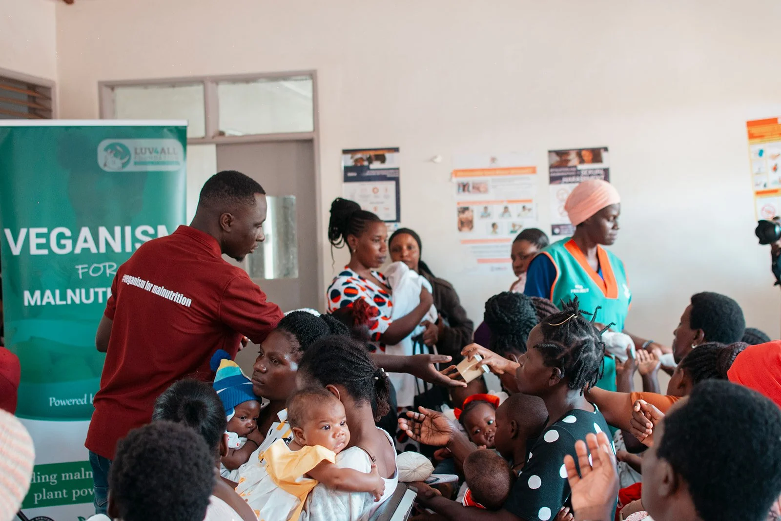 A group of women and children receiving health education and nutritional support from healthcare workers during a community outreach event focused on malnutrition awareness.
