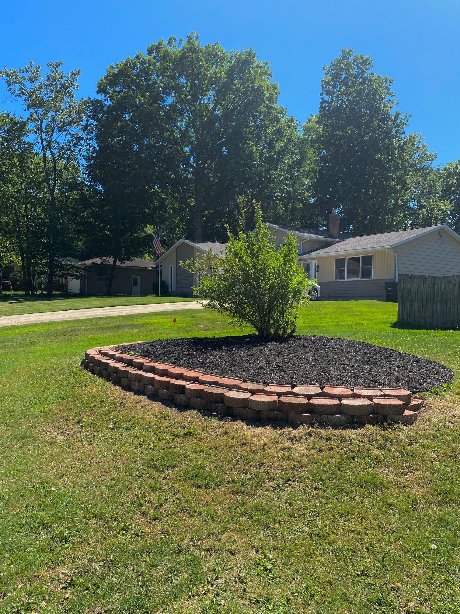 Freshly installed mulch landscape bed with brick edging in the front yard of a suburban home in North Royalton, Ohio, featuring neatly maintained landscaping and professional landscape installation by H&H Property Services.