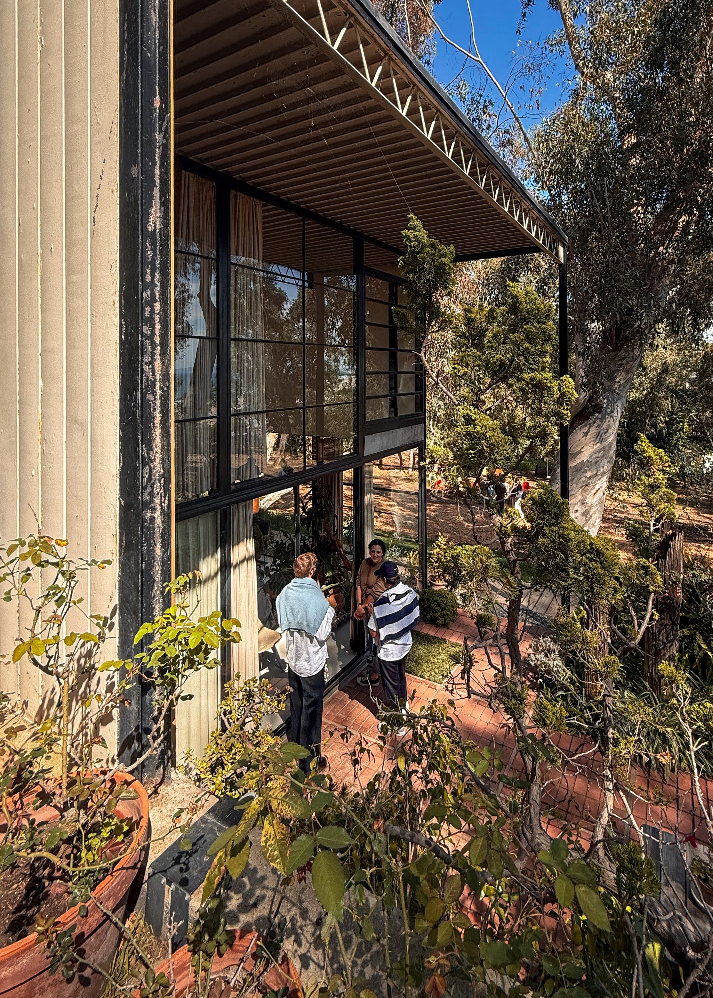 Charles and Ray Eames' Eames House in Los Angeles, California, USA, part of the Case Study House Program. Group of people chatting next to the House. Architecture photography.