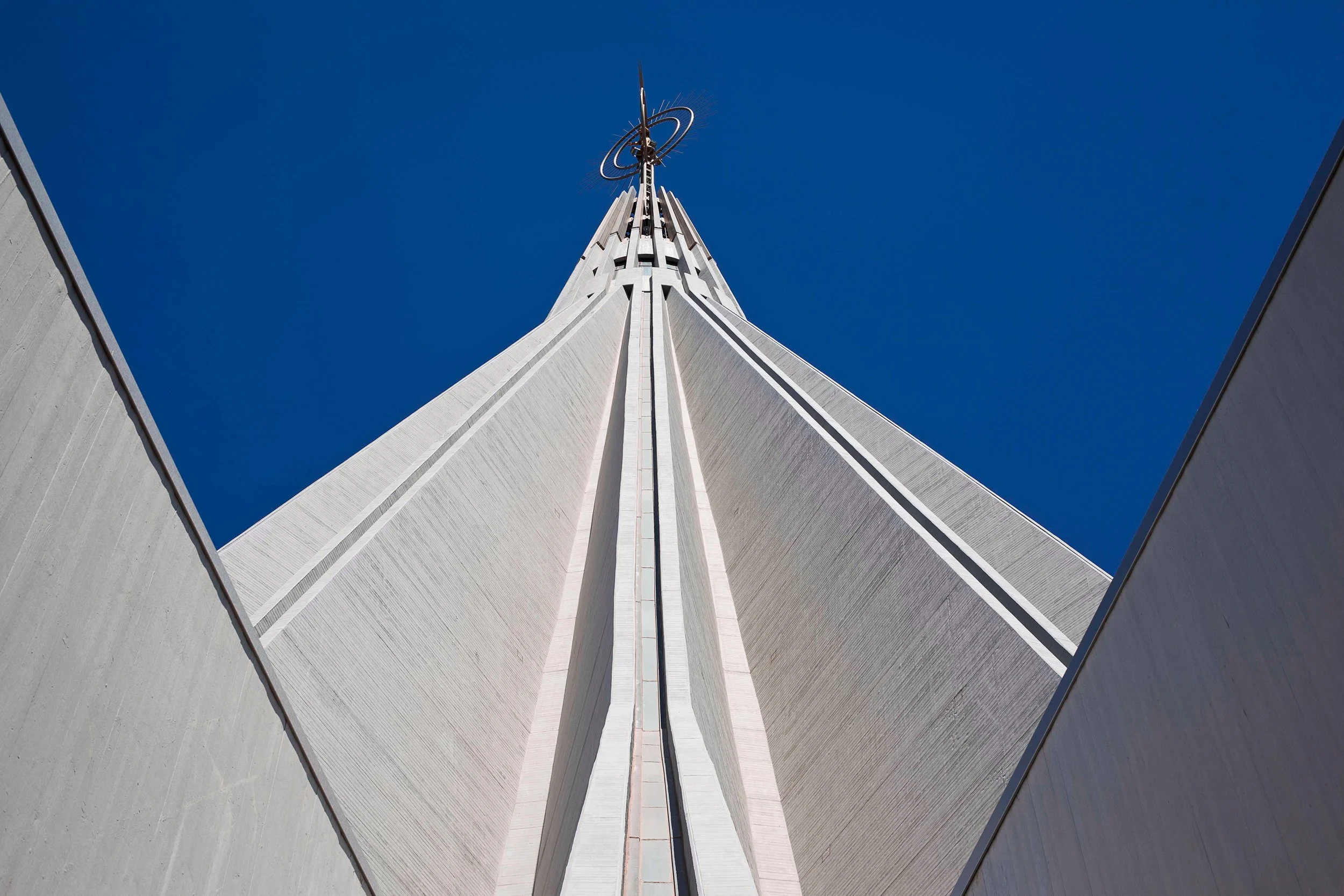 Low-angle, exterior view of the dome of the Basilica of the Madonna delle Lacrime, a Roman Catholic church in Syracuse in Sicily, Italy, against a clear blue sky.
