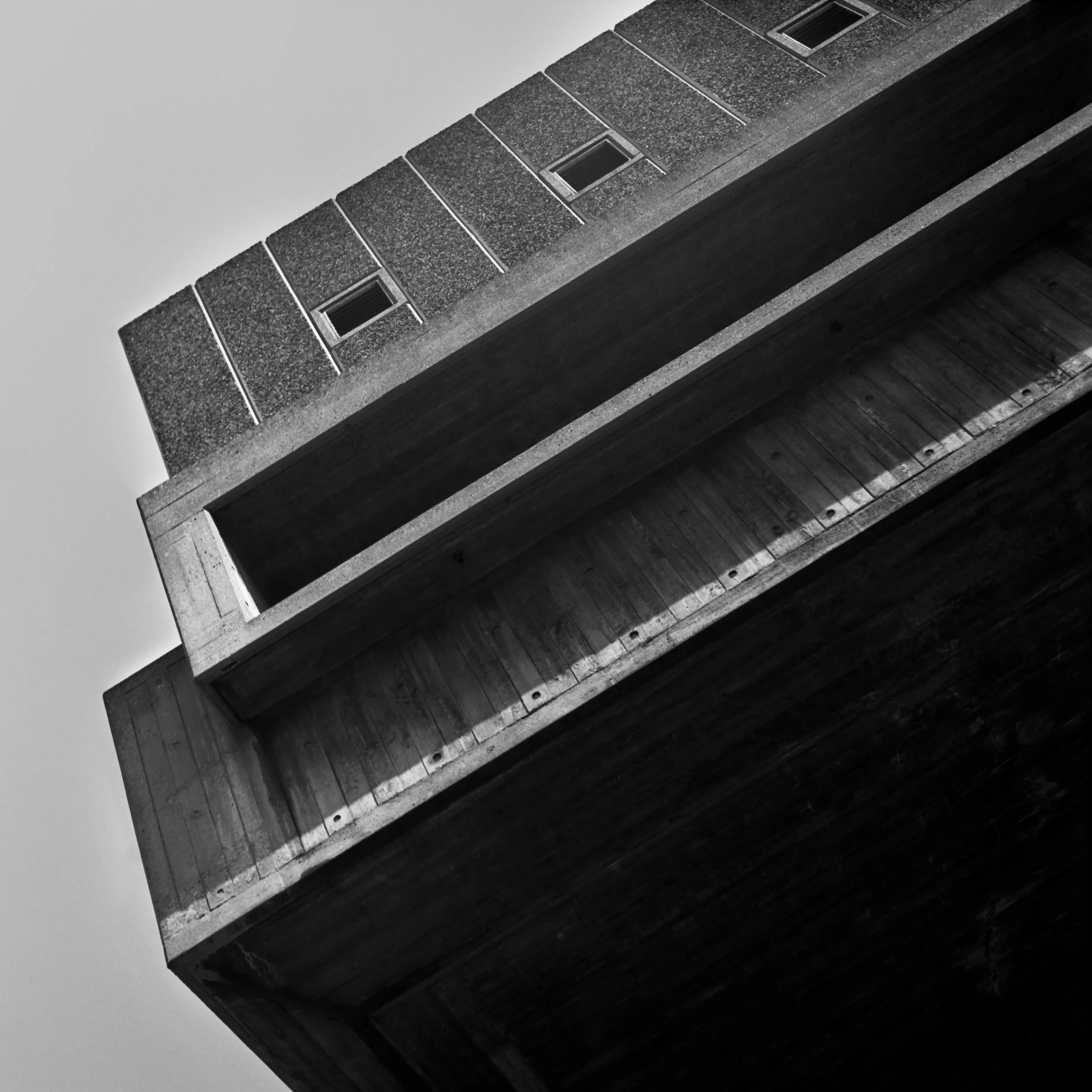 Close-up of a modern building corner with textured brick facade and small rectangular windows at the Southbank Centre in London, United Kingdom. Black and white architecture photograph.
