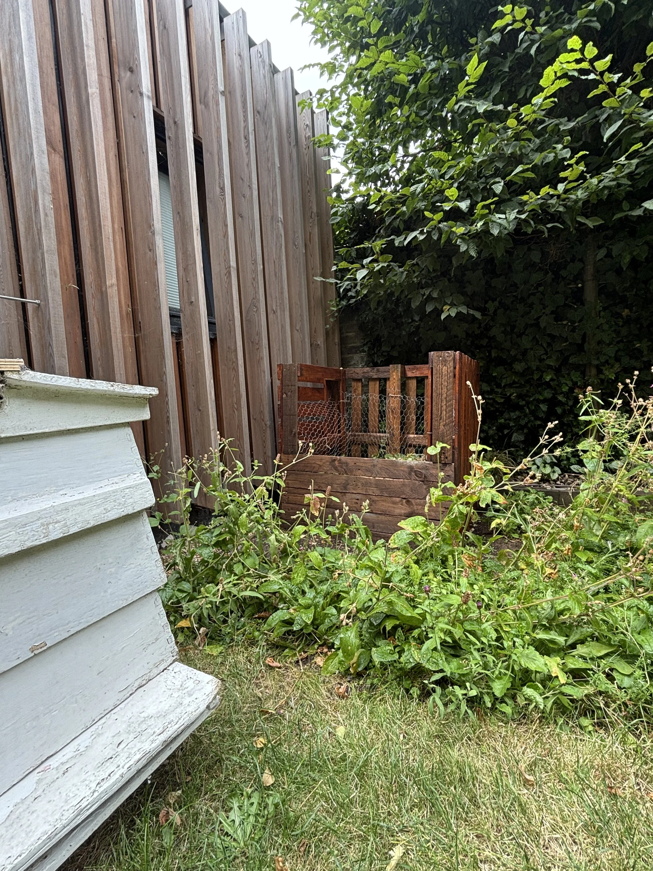 Reclaimed wood composting area built from repurposed materials for sustainable garden waste recycling and soil regeneration
