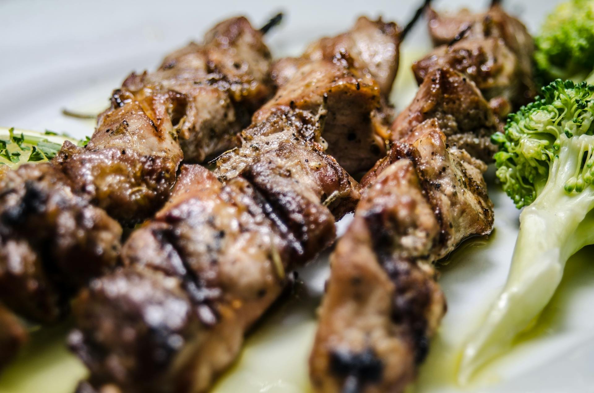 Grilled meat skewers served with fresh broccoli on a plate