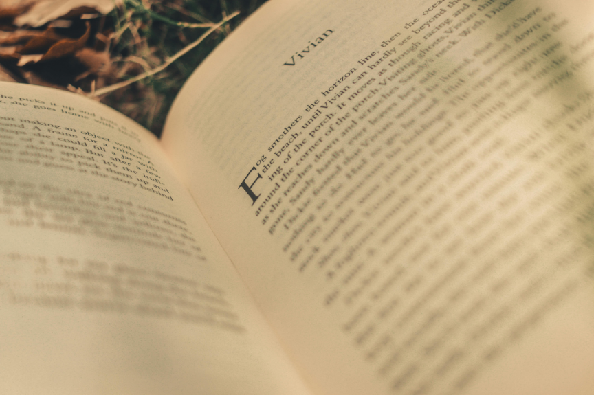 Page d'un livre ouvert avec le titre 'Vivian' visible, avec un fond flou de feuilles sèches à l'extérieur.